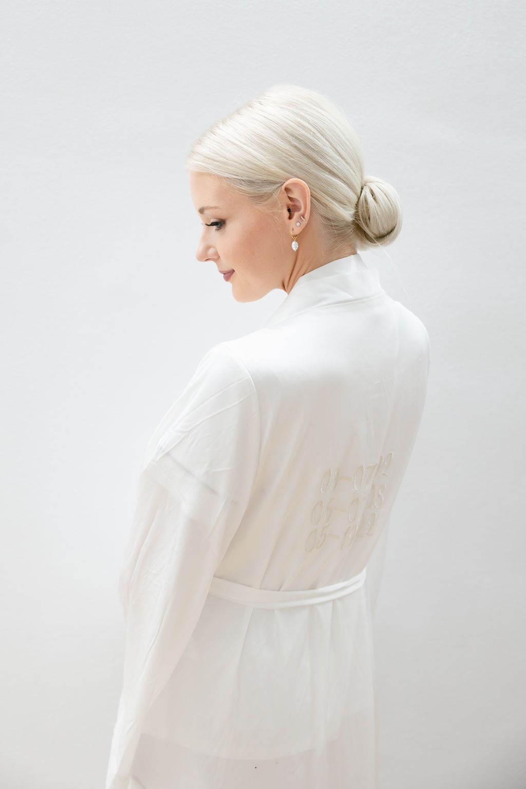 Back view of someone wearing a white outfit with blonde hair in a sleek bun.