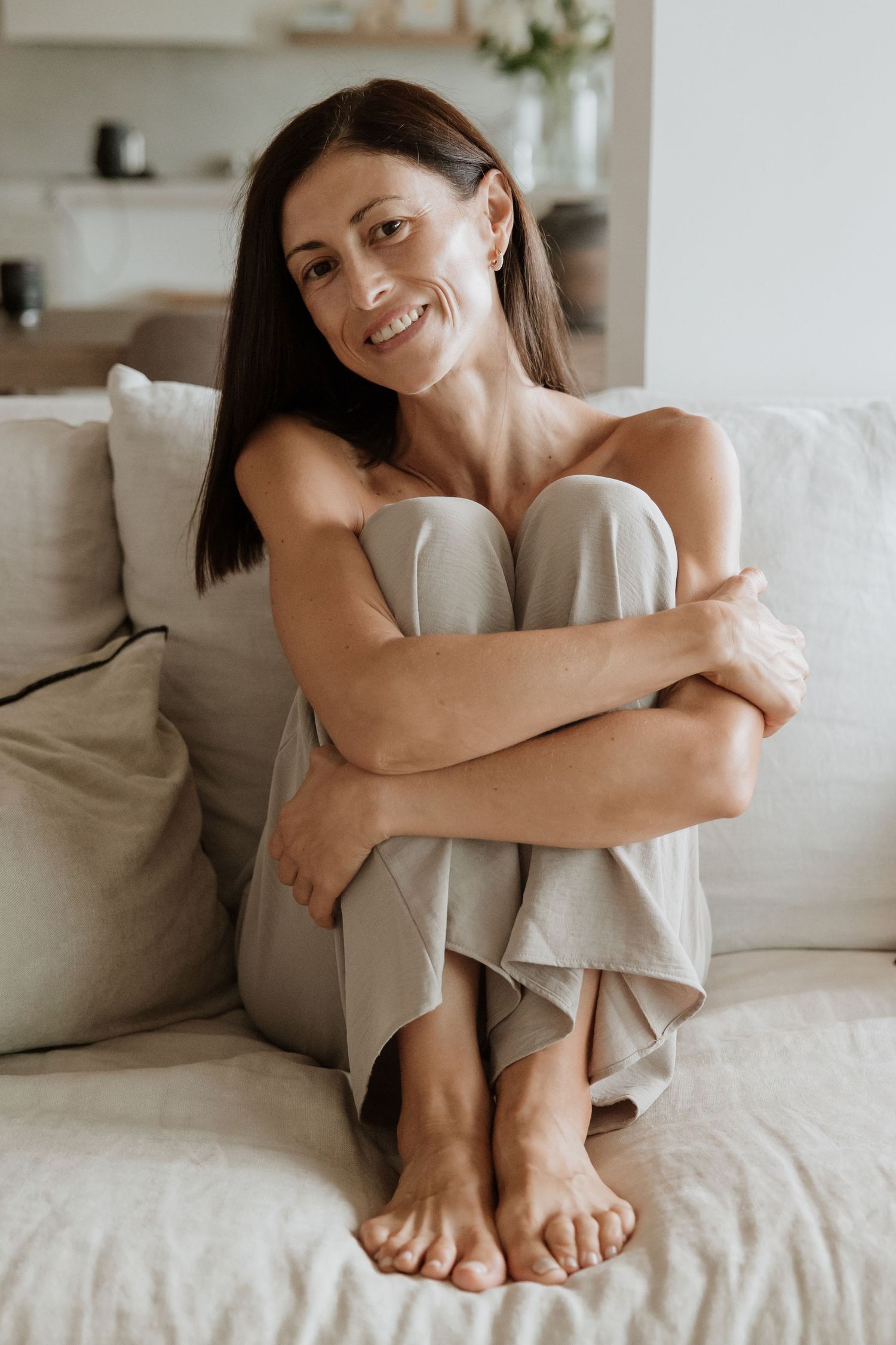 Candid lifestyle photo on white couch showcasing relaxed casual pose.