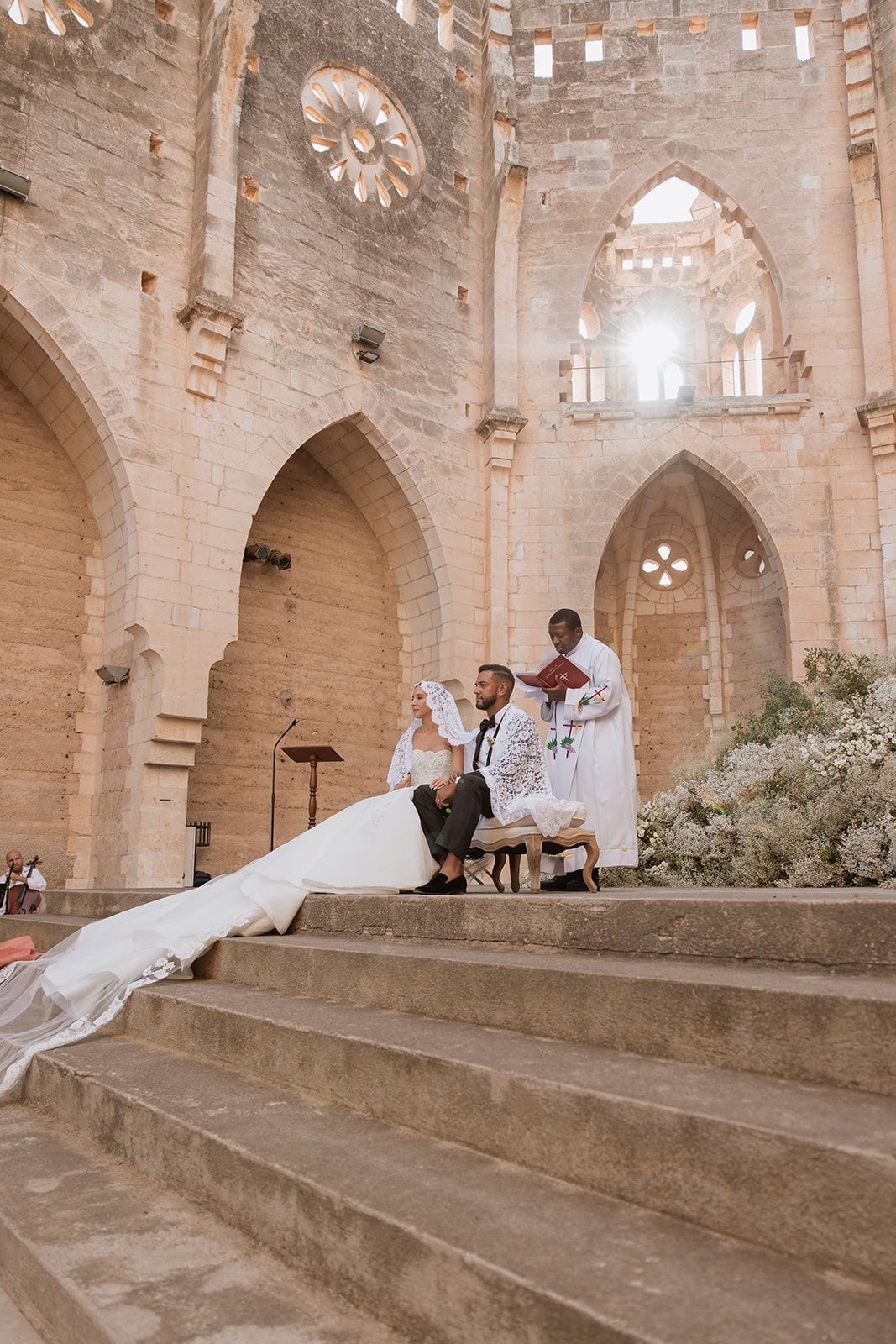 Wedding dress train flowing down cathedral stone steps during photo session.