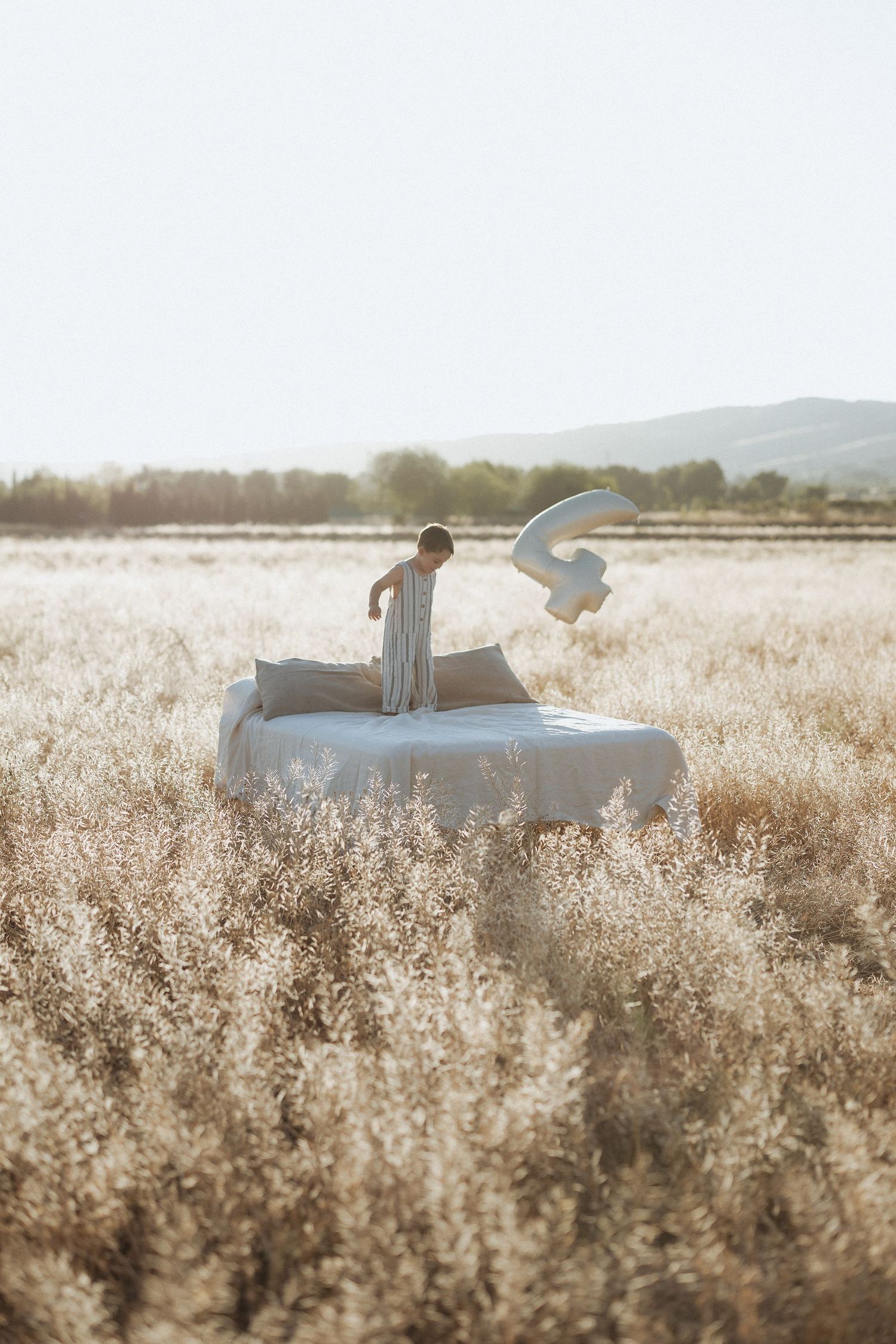 A person relaxes on a blanket in a serene golden field of tall grass during sunset.