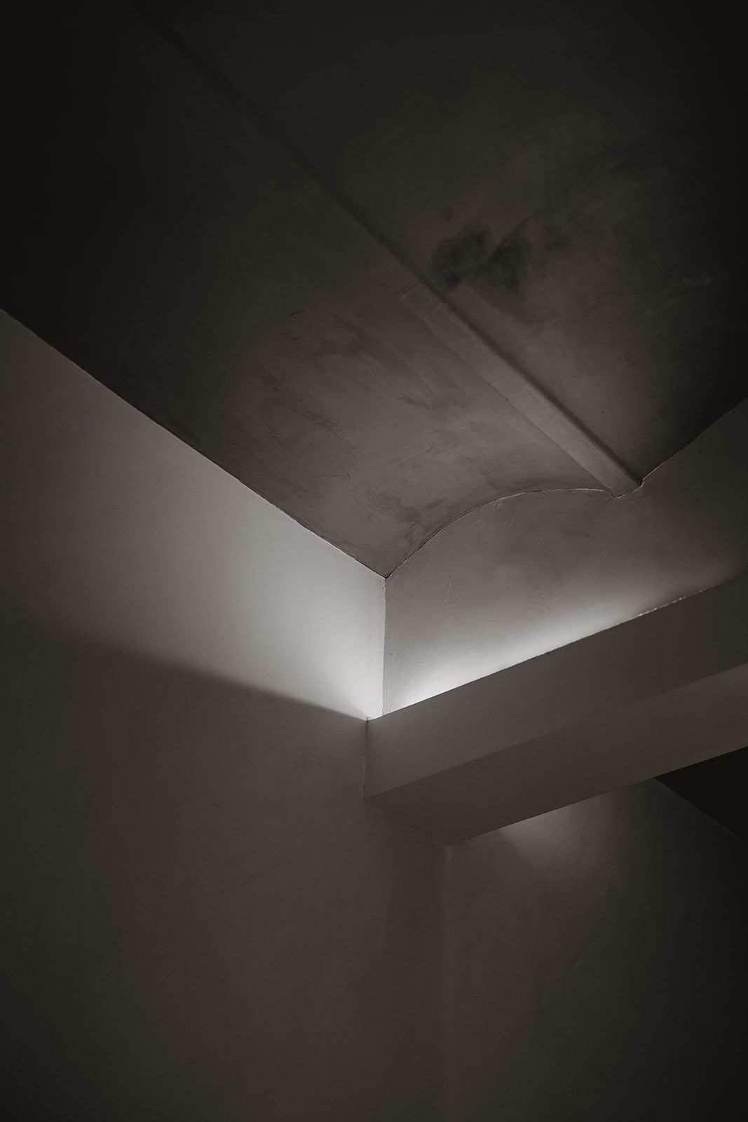Minimalist architectural detail of a corner ceiling with dramatic shadows and lighting.