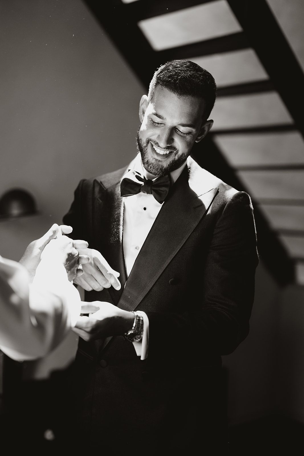 Black and white photo of person in tuxedo sharing an intimate moment during a formal event.