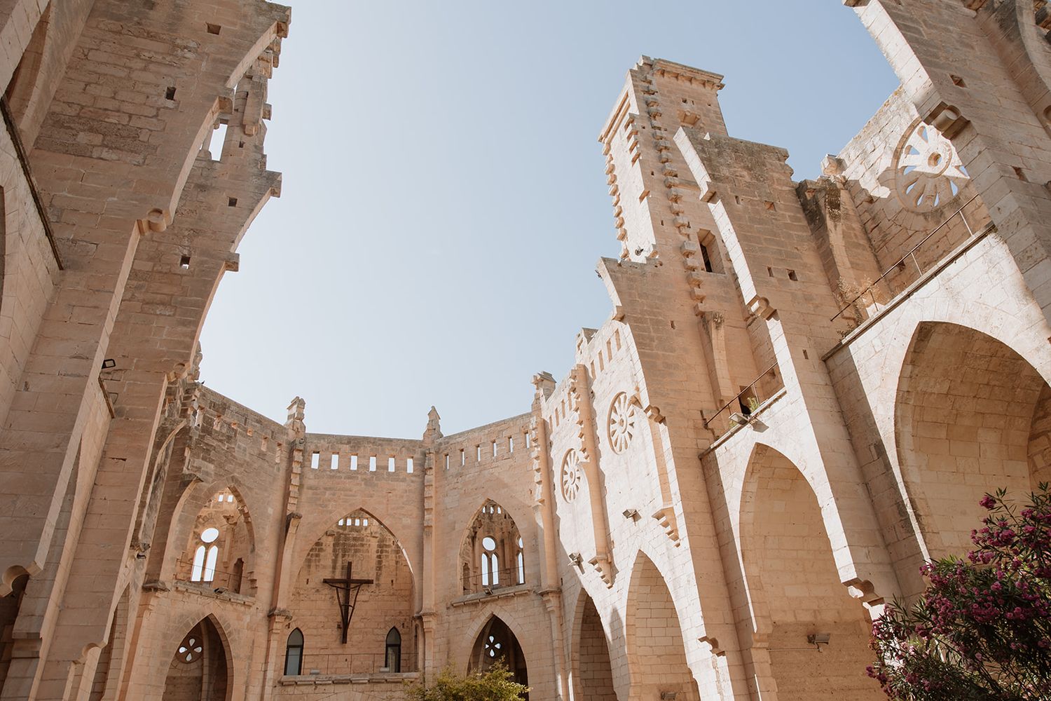 Sun-lit stone castle ruins featuring grand arched windows and dramatic architectural details.