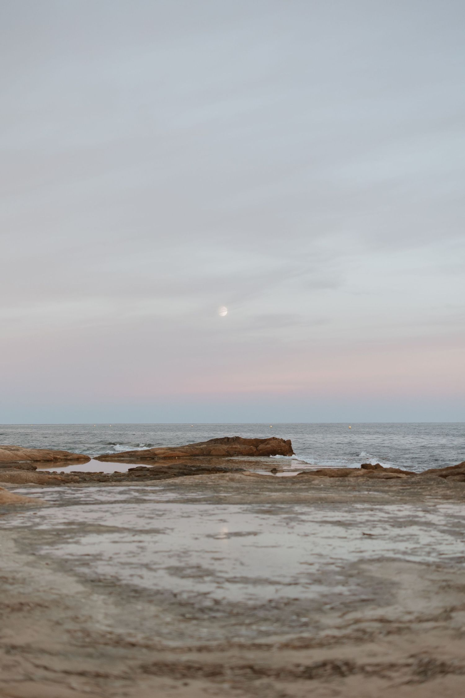 Serene seascape with rocky coastline and pastel sky at dusk.