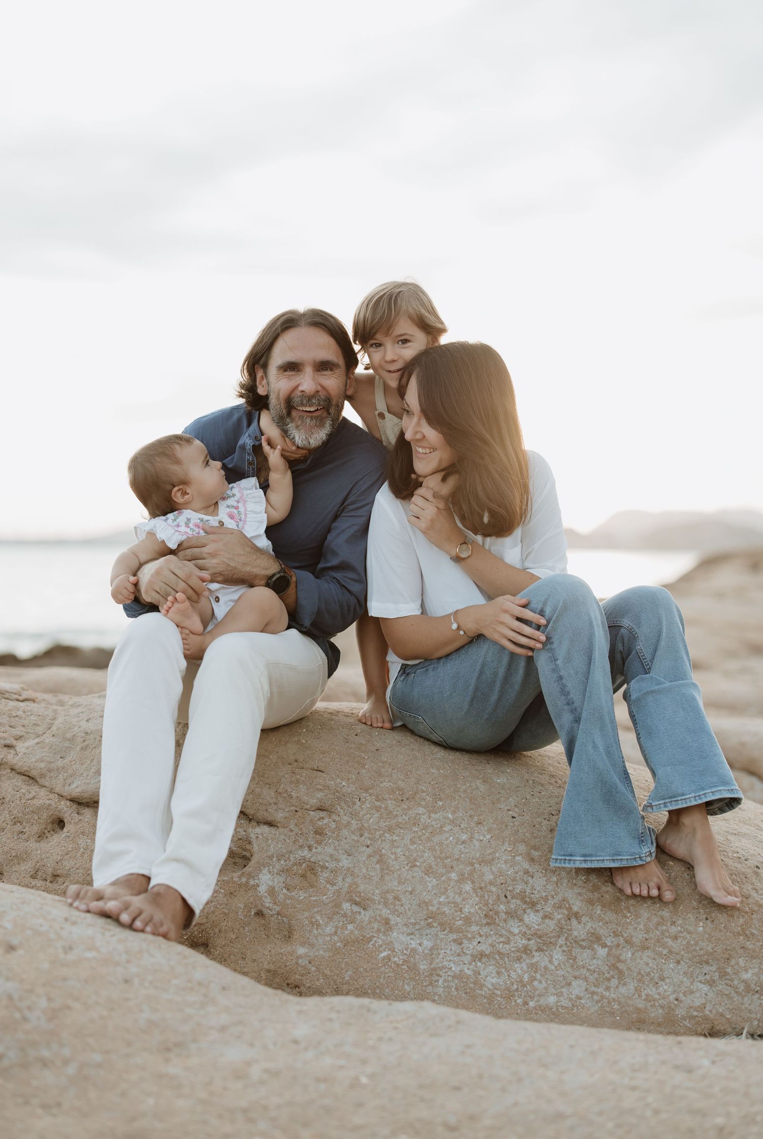 A candid family moment captured on rocky terrain near the ocean.