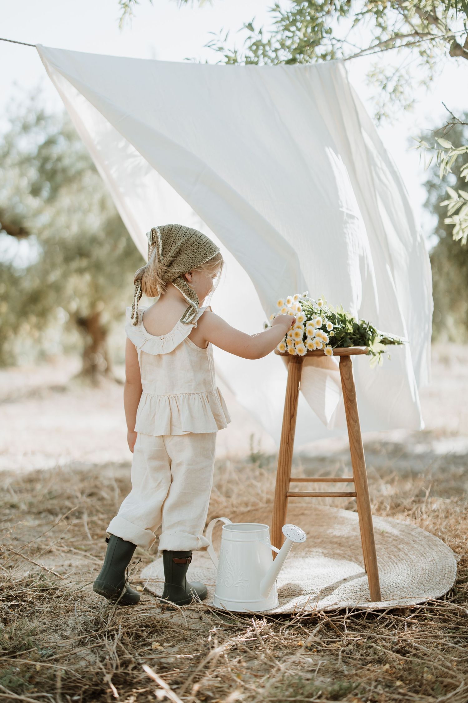 Sunlit outdoor scene with white linens hanging between wooden posts.
