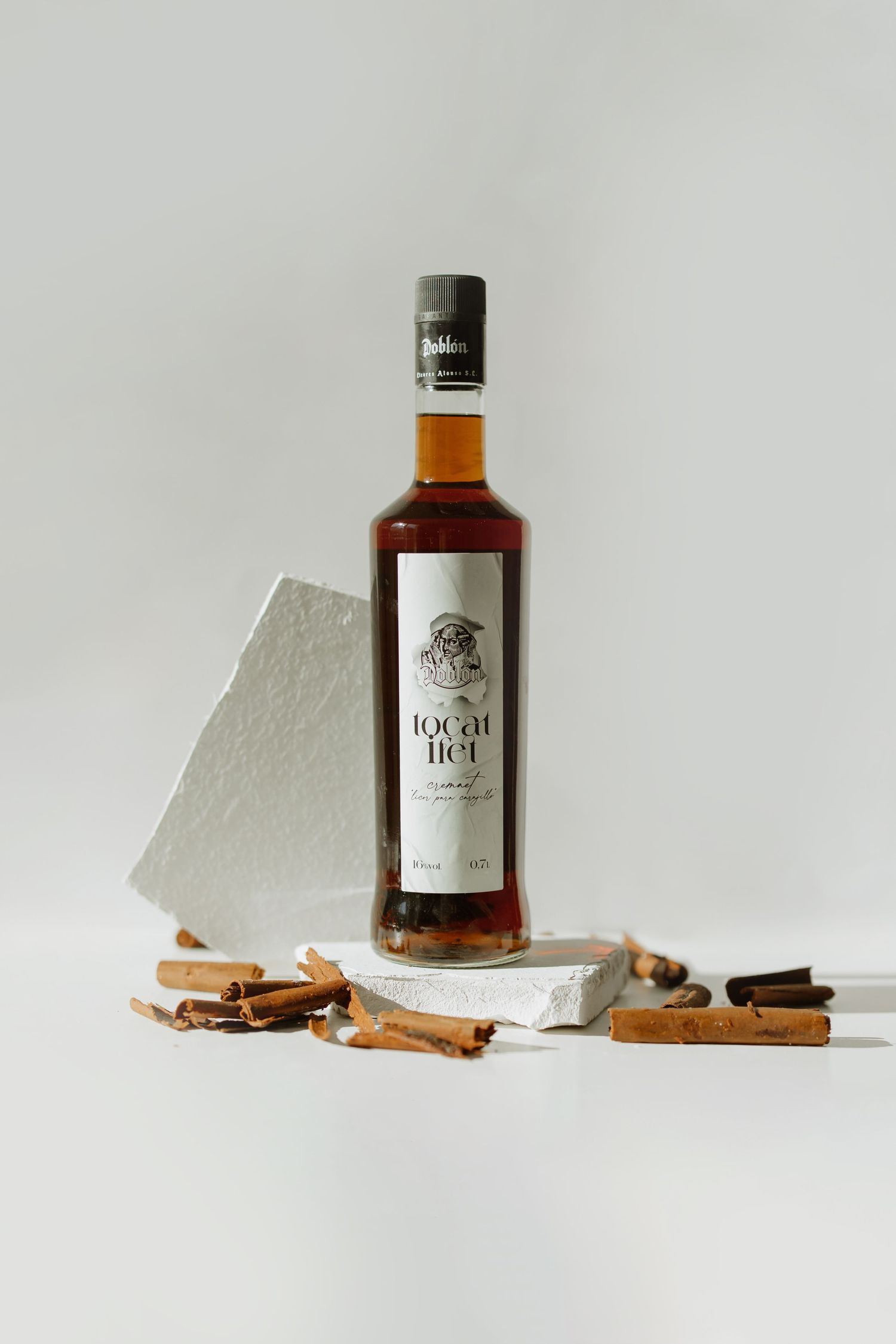 A bottle of Local 104 spirit styled with cinnamon sticks and white geometric shapes.