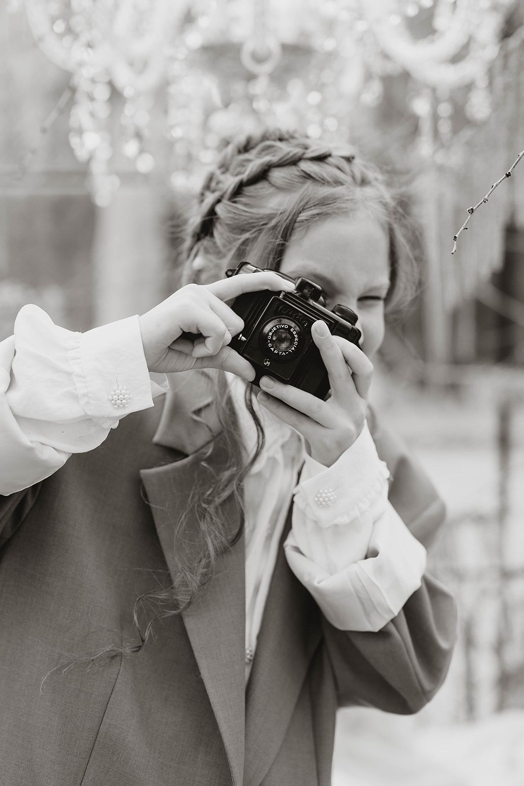 Black and white portrait of photographer with braided hair using vintage camera.