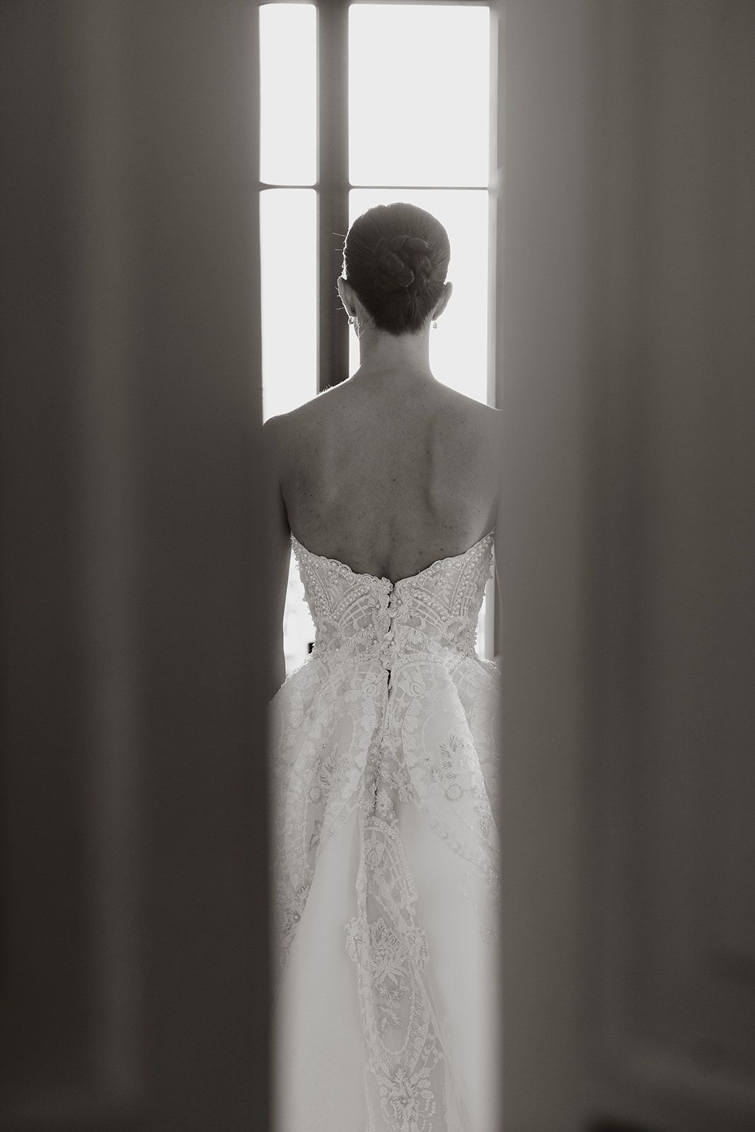 Dramatic black and white silhouette showing back details of a fitted wedding gown.