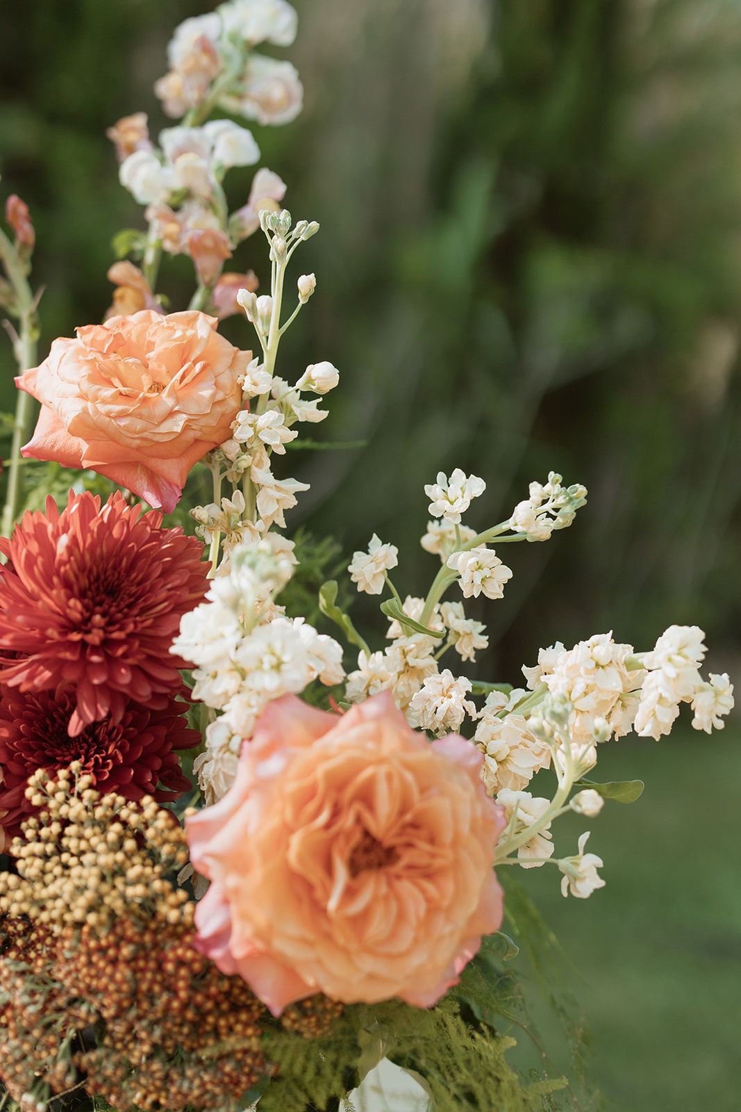 Romantic floral arrangement with peach roses, burgundy dahlias, and white delicate blooms.