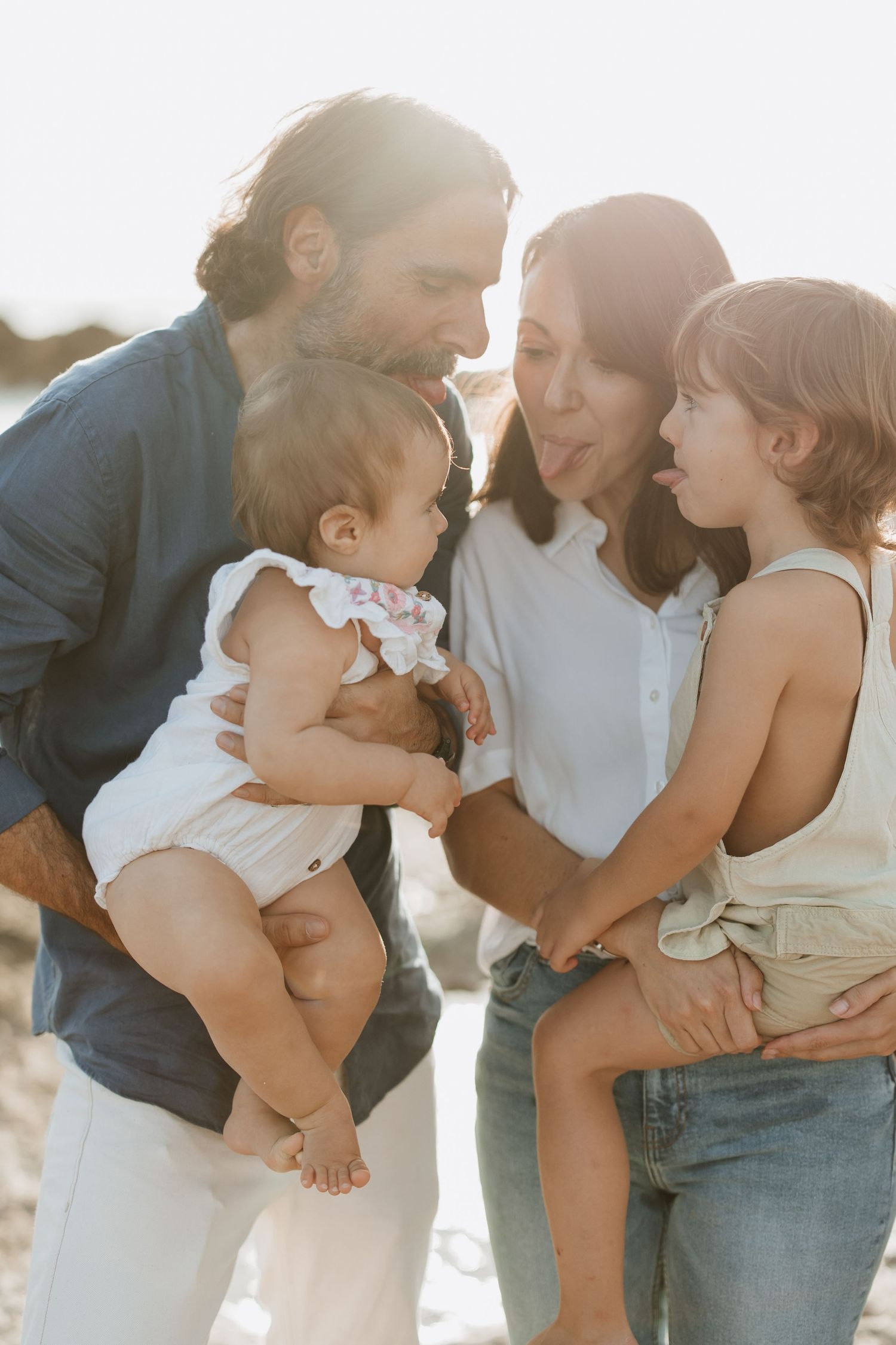 An intimate family moment captured in warm sunlight by the ocean.