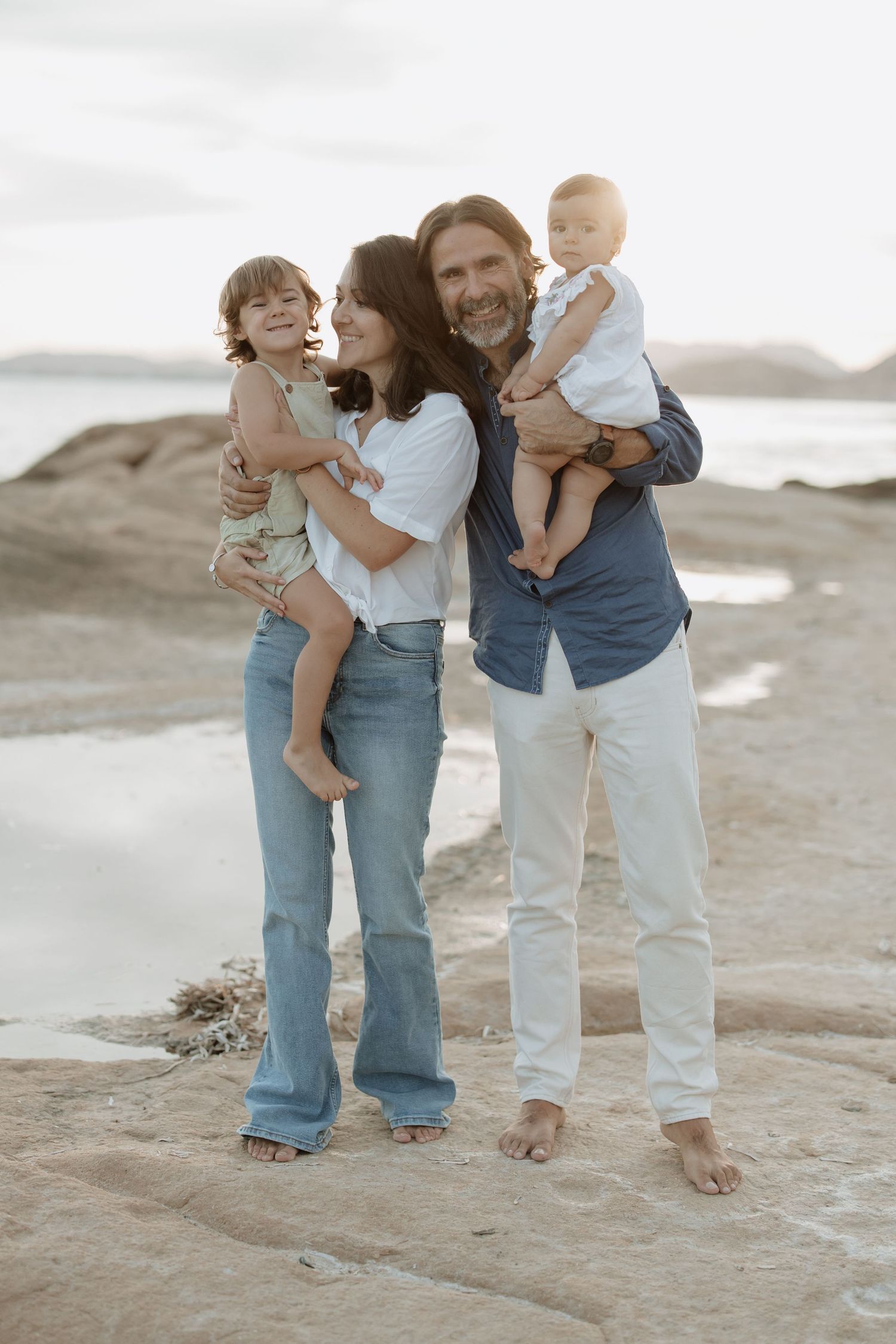 Candid family photo session on rugged beach terrain.