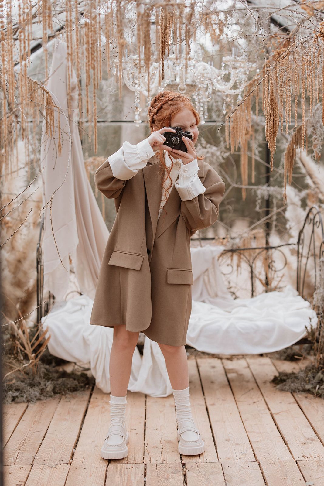 Figure in brown blazer and white dress shirt taking photos against a dreamy autumn backdrop.