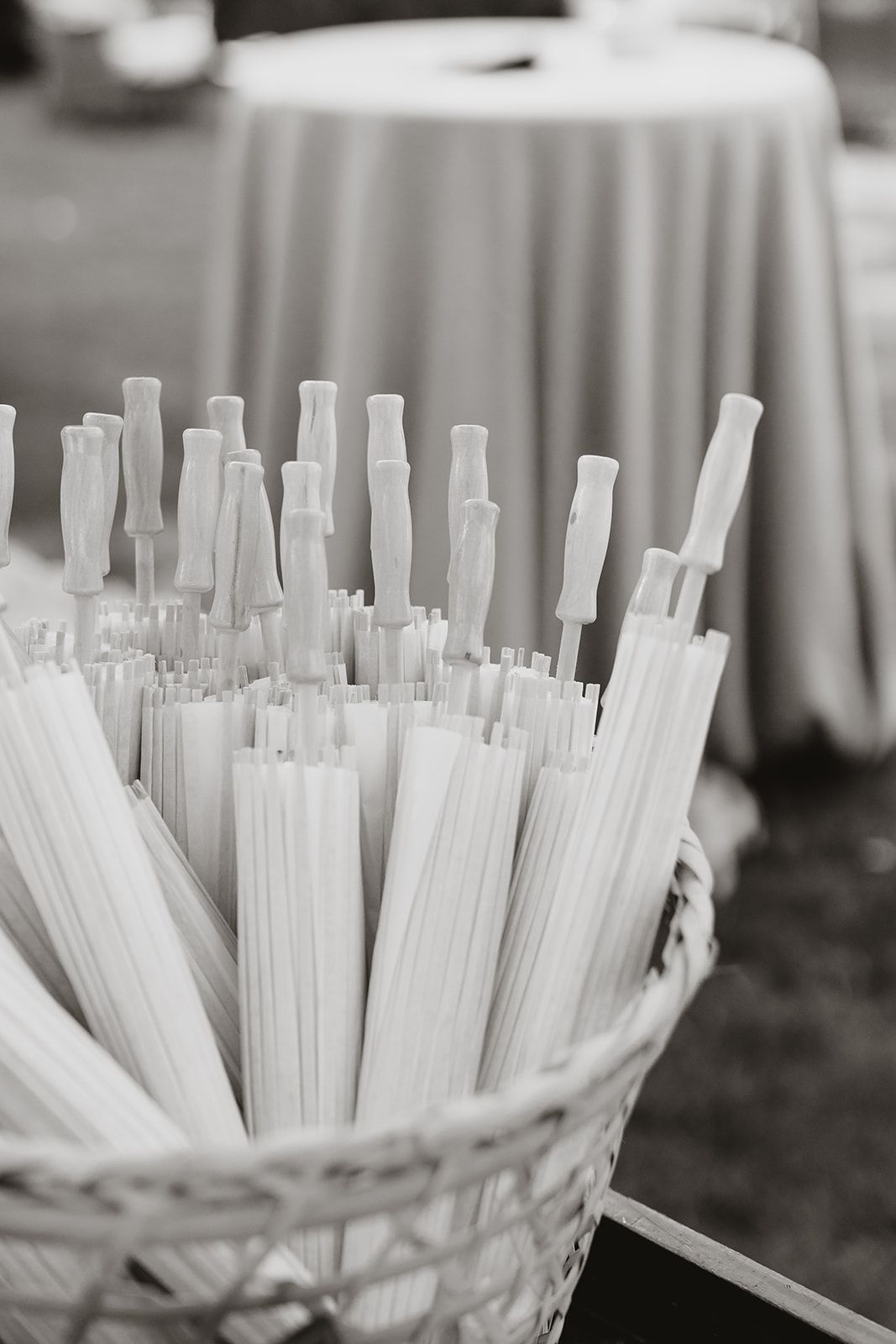 White paper drinking straws arranged in a wicker basket at a wedding reception.