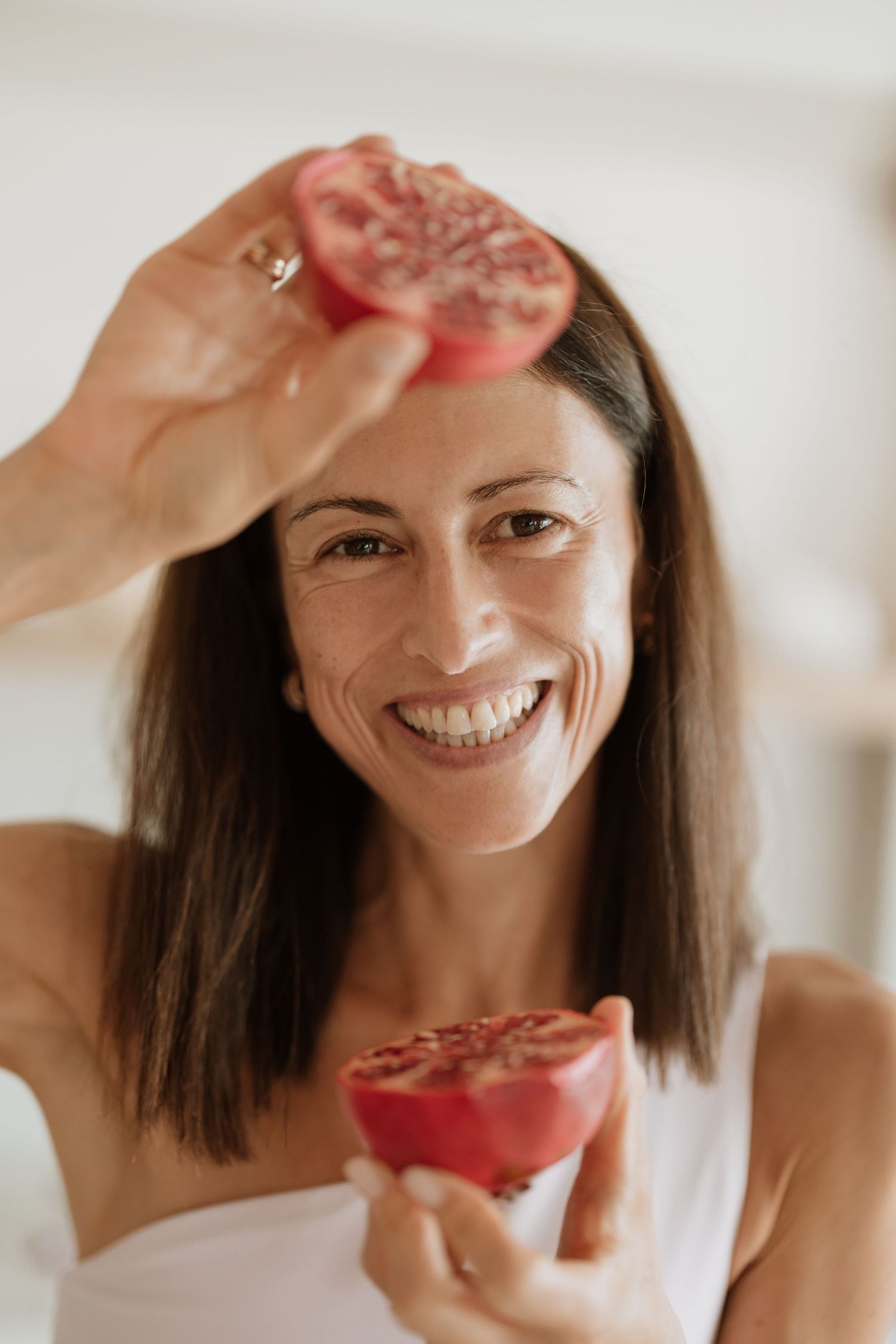 Someone holding a halved pomegranate against a bright white kitchen background.