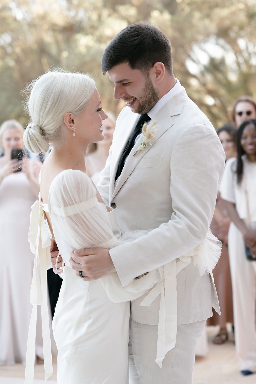 The couple shares a joyful moment in matching white attire during their wedding celebration.