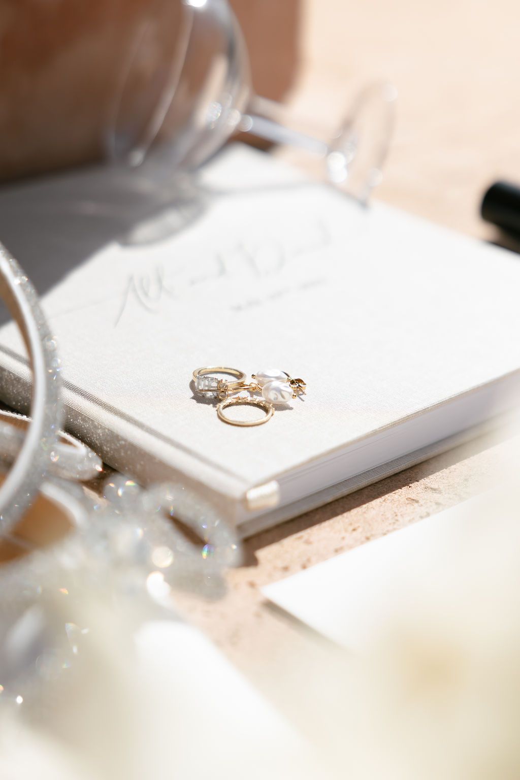 Wedding rings displayed on white invitation card with champagne glasses.