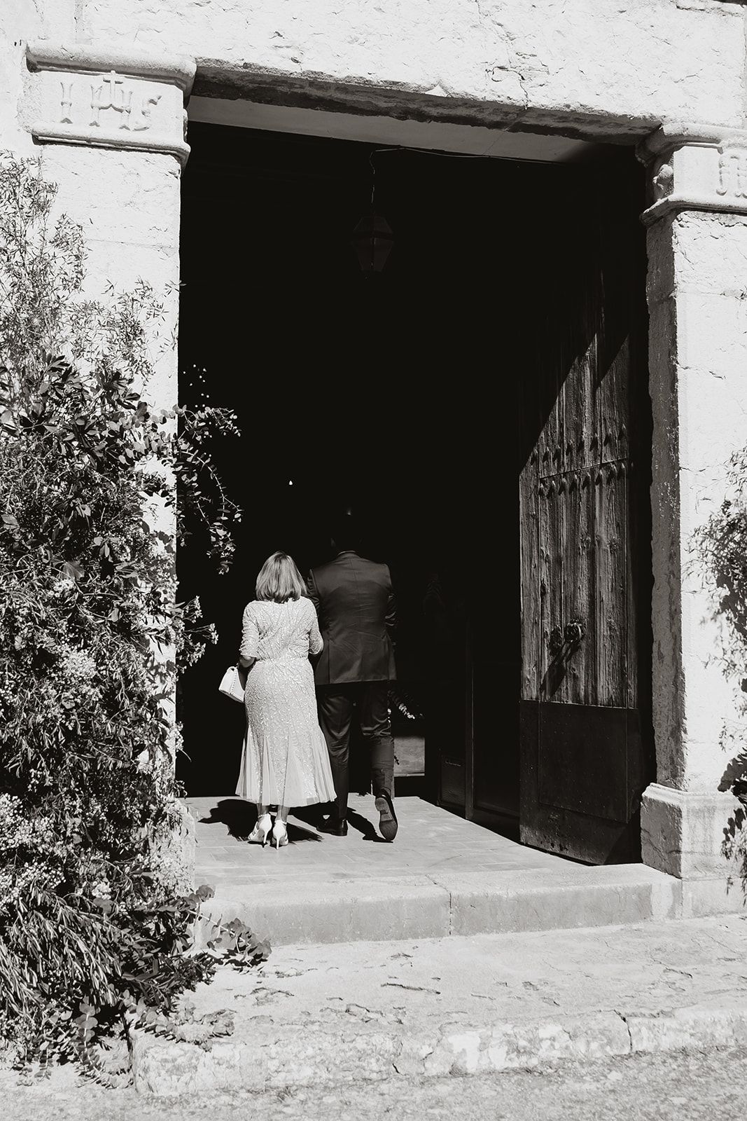 Black and white photo of couple entering through rustic church doorway.