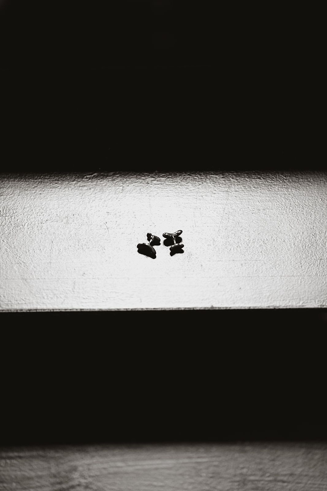Minimalist black and white photo of cufflinks on white surface.