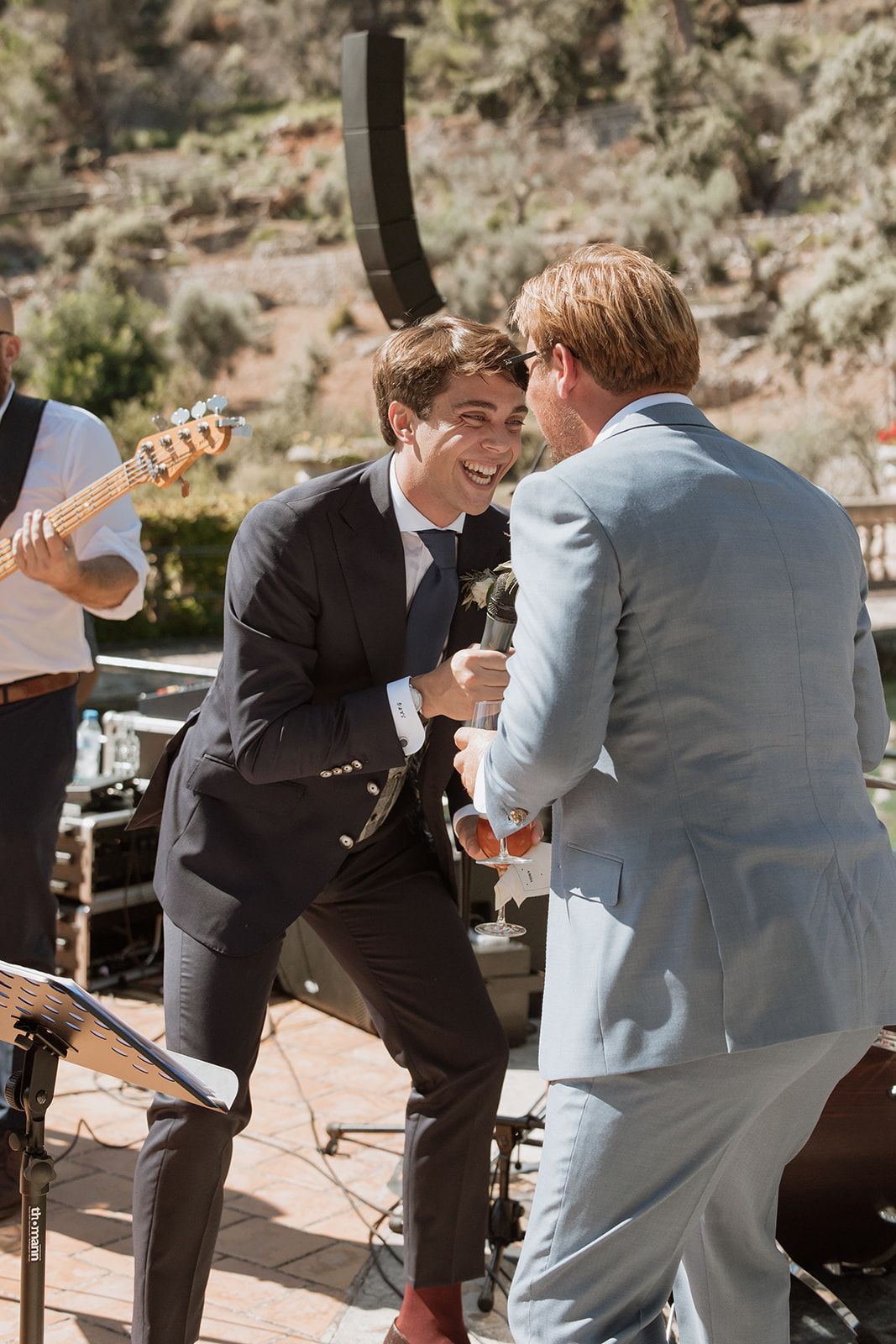 Two performers sharing microphone and singing together on outdoor wedding stage.