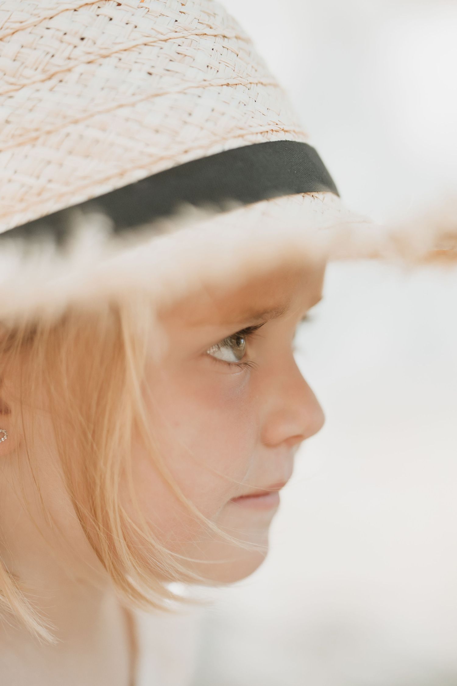 Dreamy side profile portrait with straw hat and soft natural lighting.