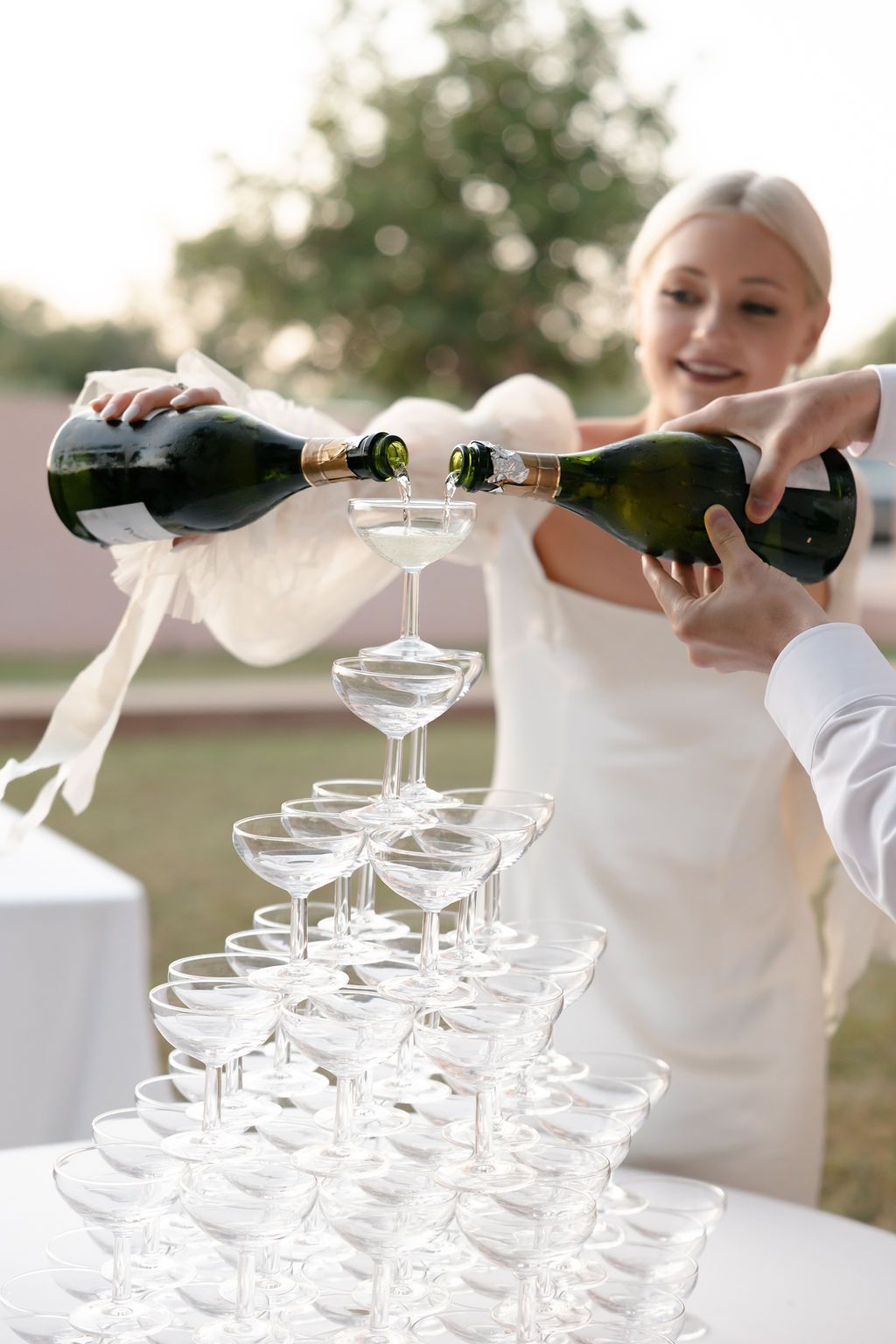 Wedding celebration featuring champagne being poured into elegant glass tower display.