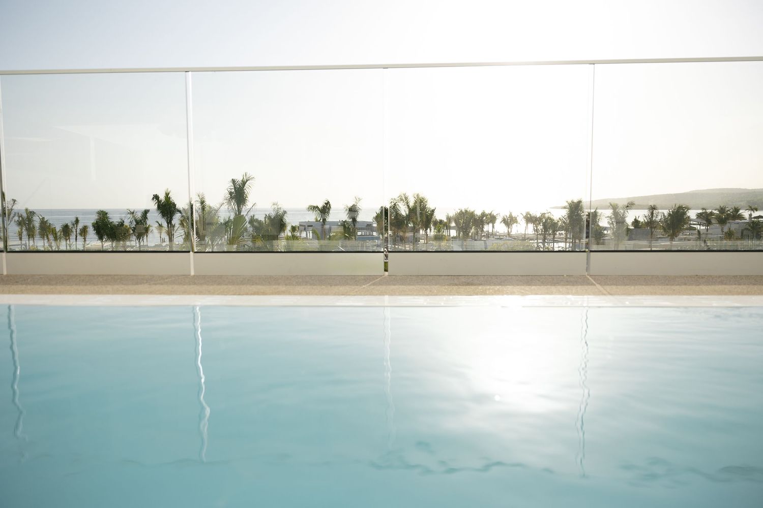 Panoramic view of an infinity pool with palm trees visible on the horizon.