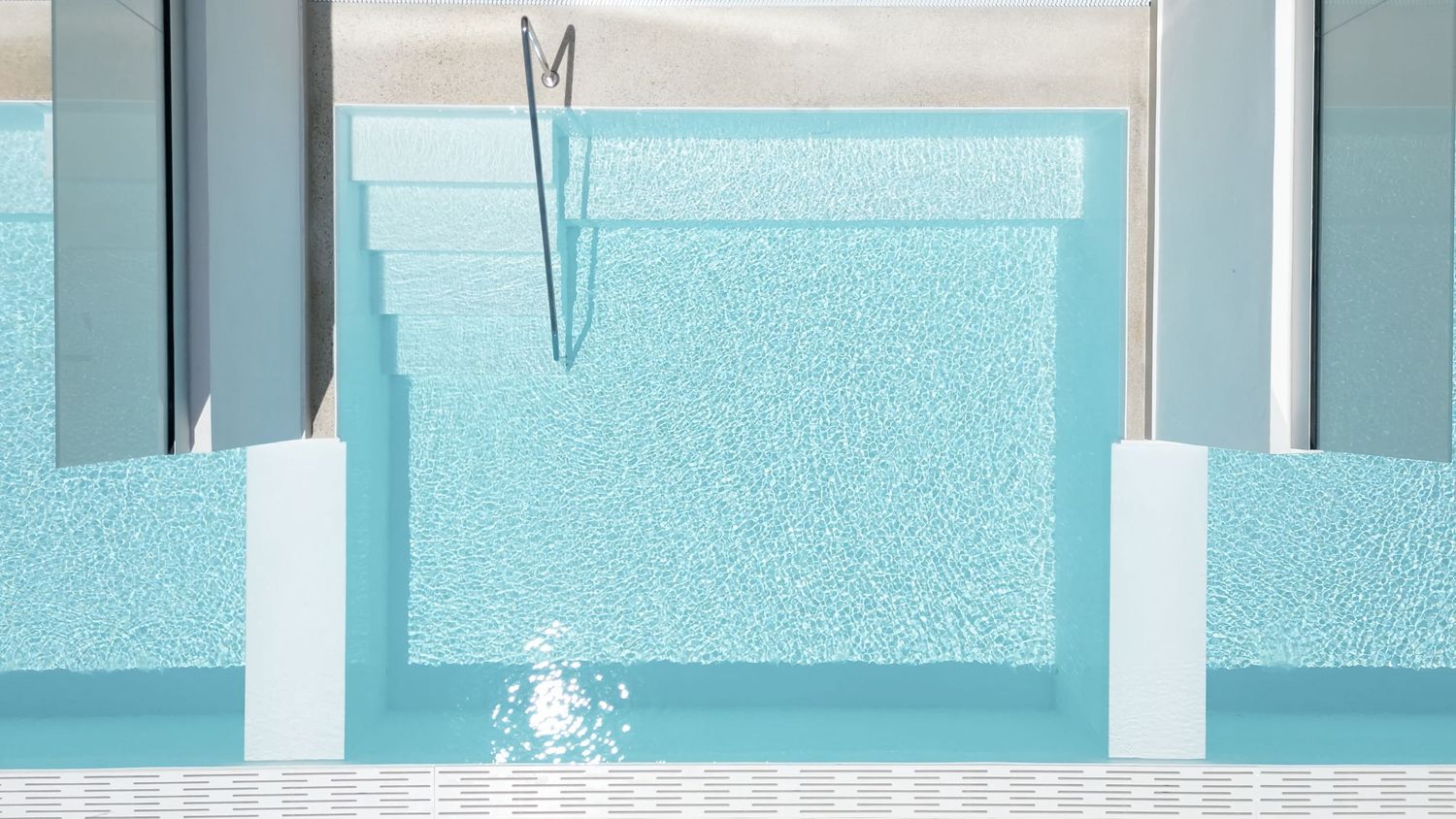 Closeup of sparkling blue private plunge pool with minimalist white architectural details.