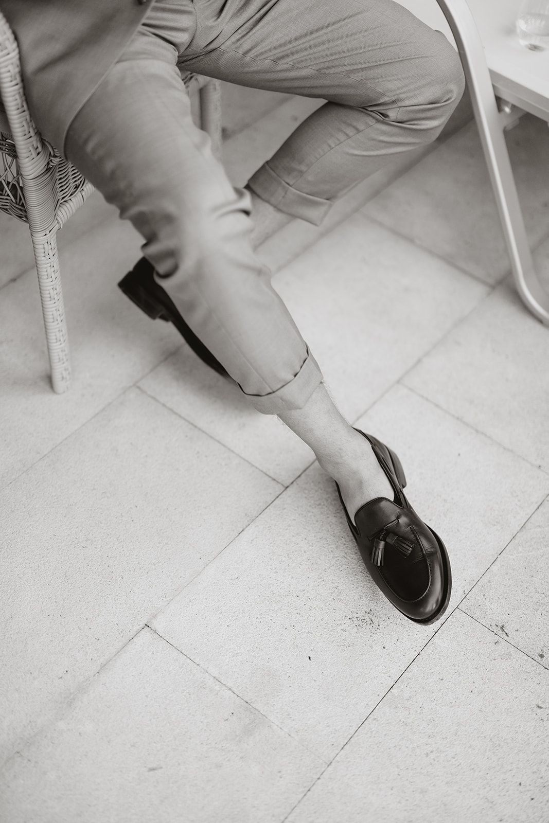 Black and white detail shot of legs wearing dress shoes on tiled floor.