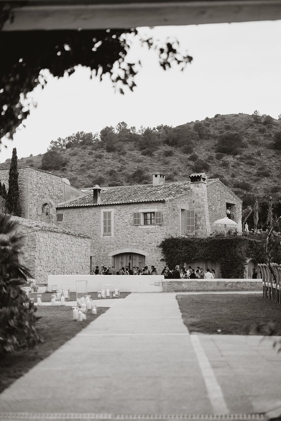 Black and white photo of a Mediterranean-style villa with stone facade and outdoor ceremony setup.