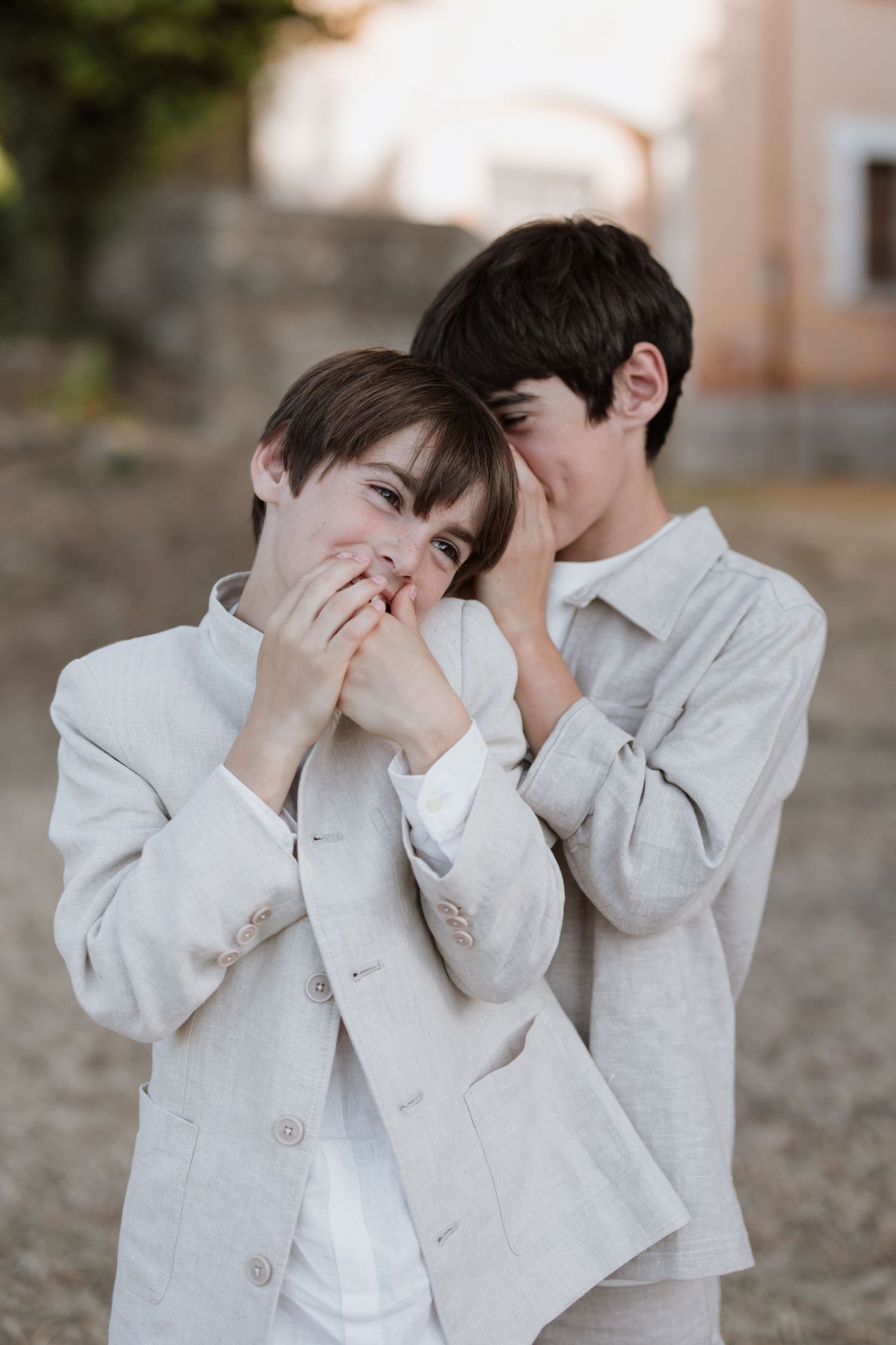 Two people in matching light gray outfits share a playful candid moment together while laughing.