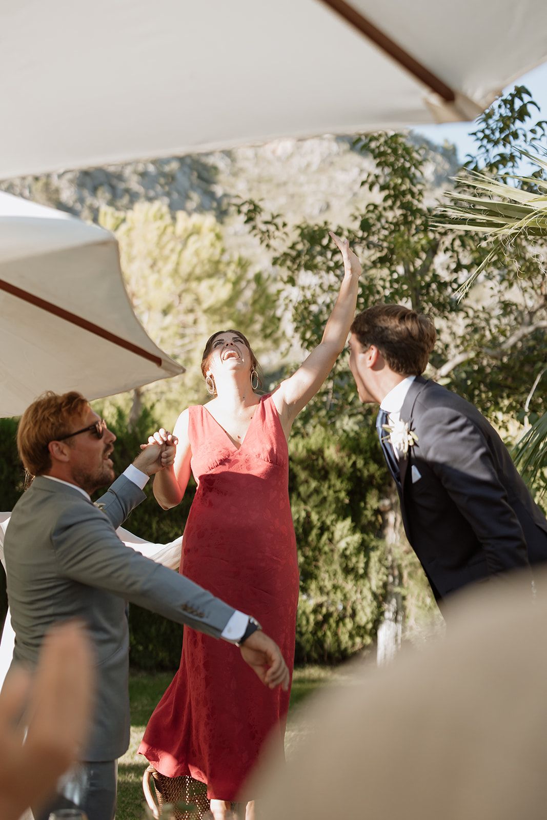 Wedding guests dancing and celebrating at an outdoor reception under a white tent.