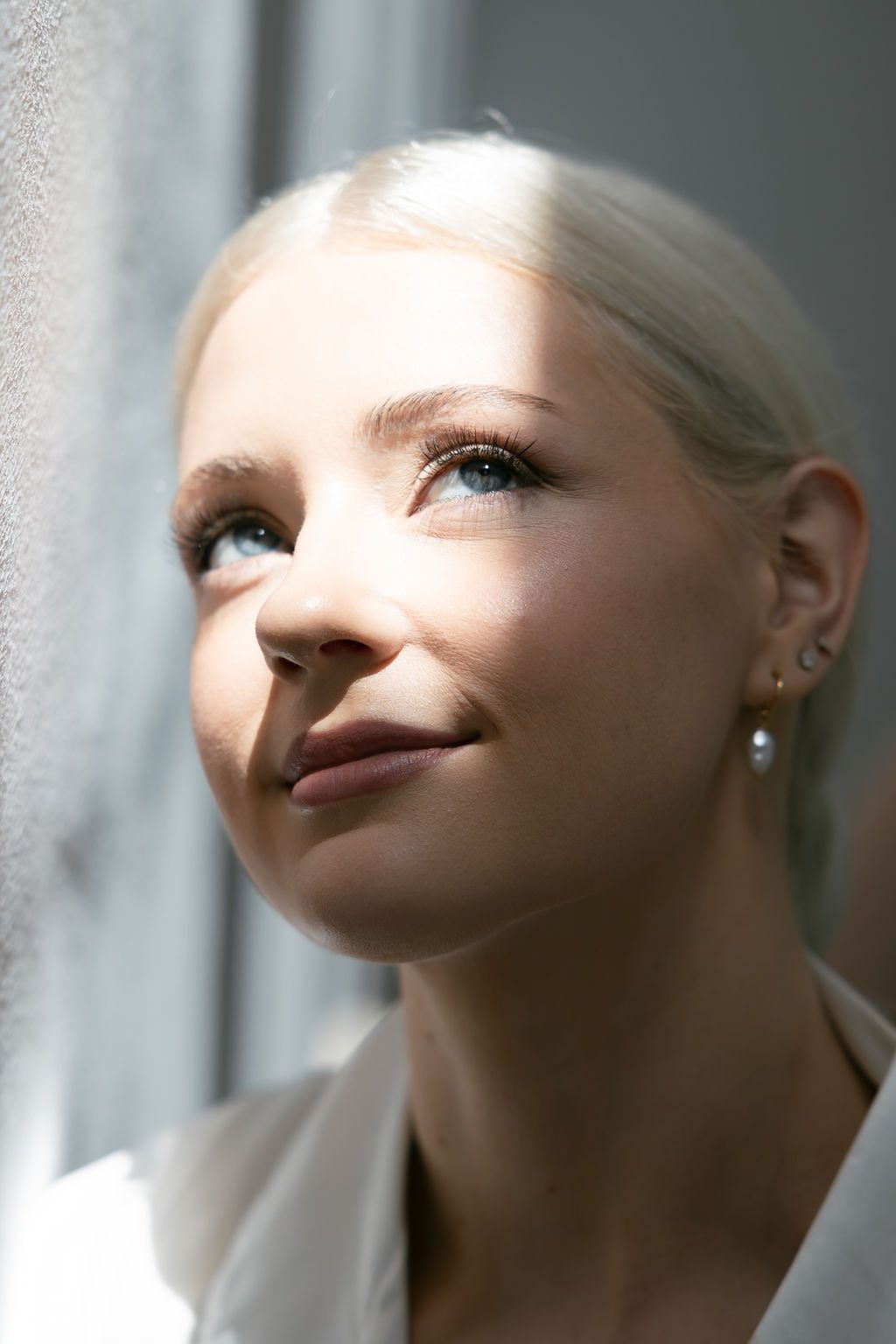 Portrait of person in white near window with natural lighting.