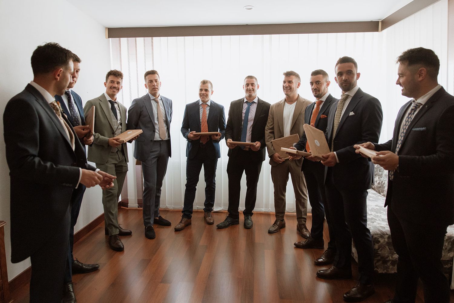 Wedding party groomsmen gathered in a circle reading letters at a celebration.