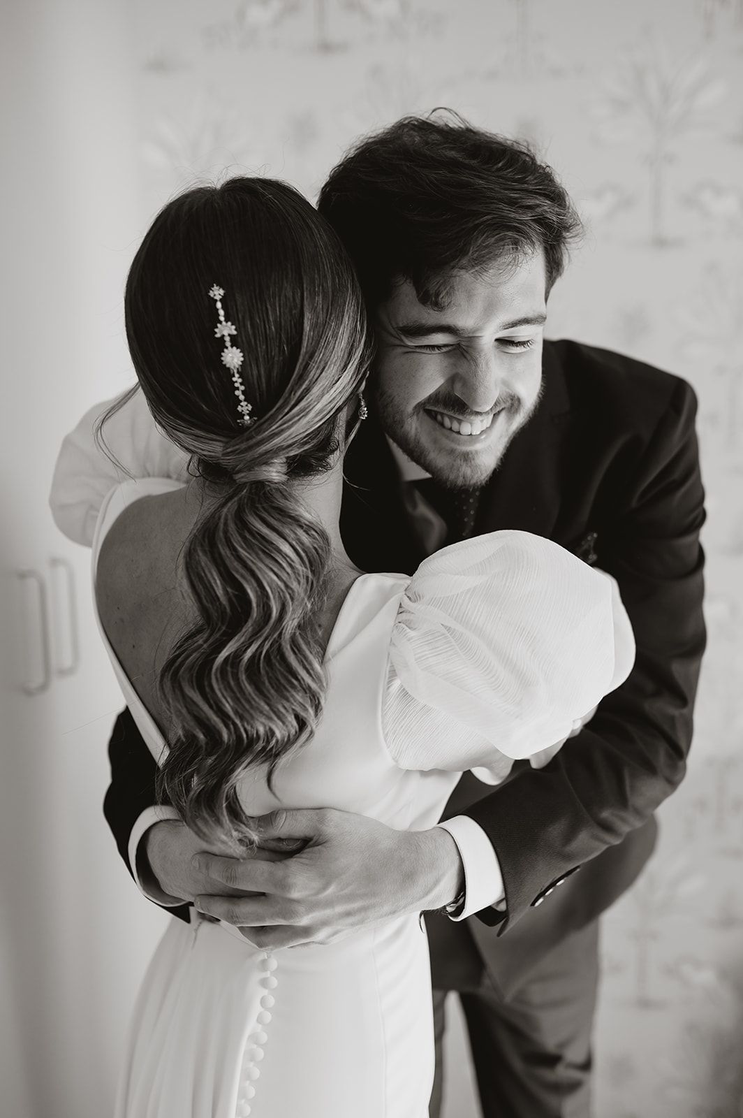Black and white romantic wedding portrait with vintage floral wallpaper background.