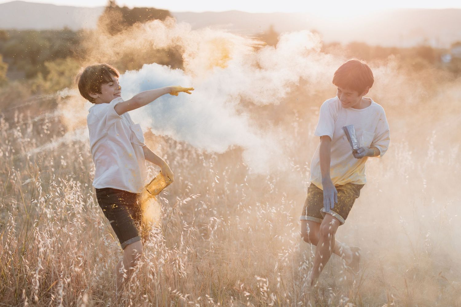Two children play in a golden field during sunset as dust particles swirl around them creating a dreamy atmosphere.