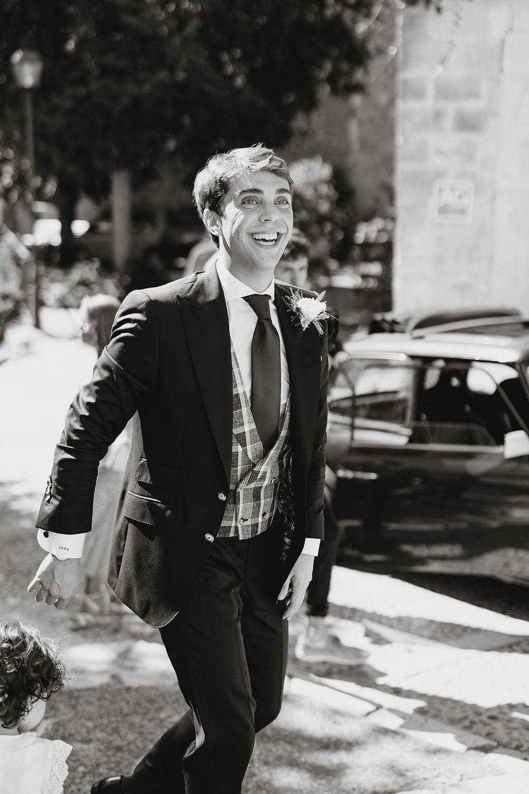 Joyful person in formal attire smiling while walking outdoors.