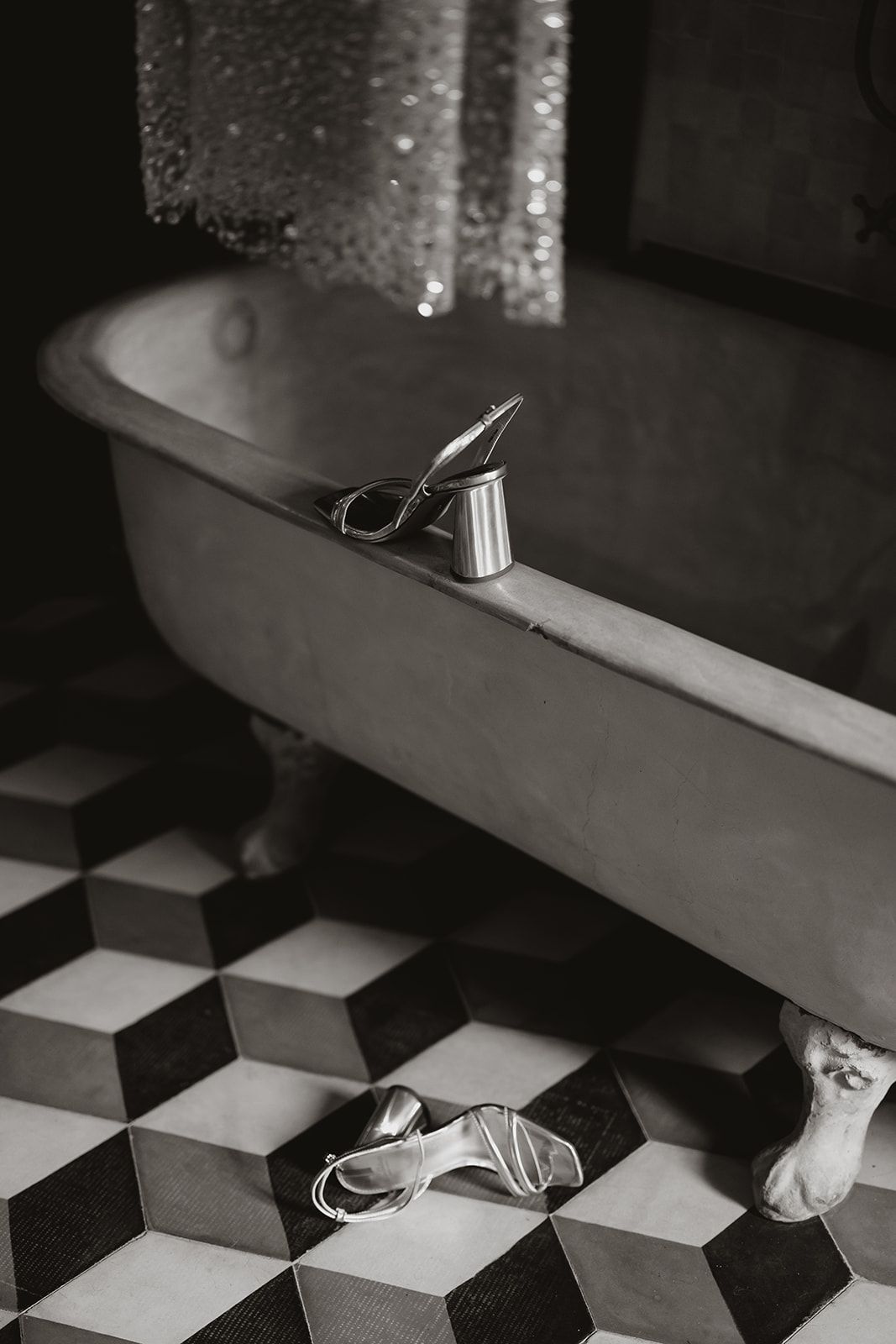 Vintage bathtub with geometric tiled floor and toiletries in black and white.