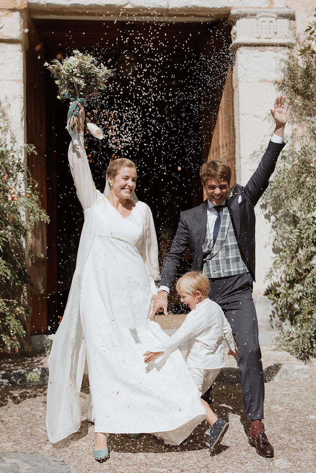 Newlyweds celebrate with rice being thrown as they exit the church entrance.