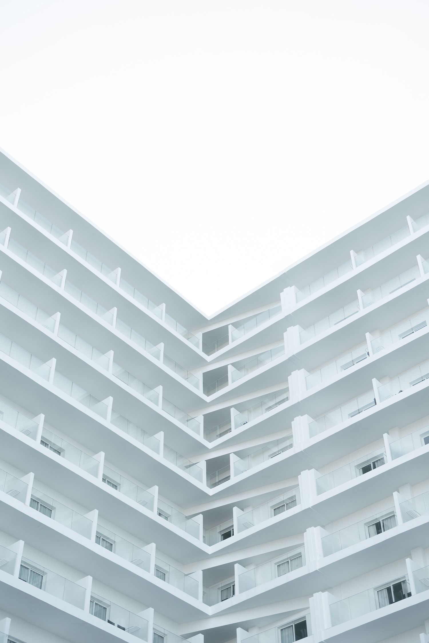 Minimalist architectural detail of white hotel balconies creating geometric patterns.