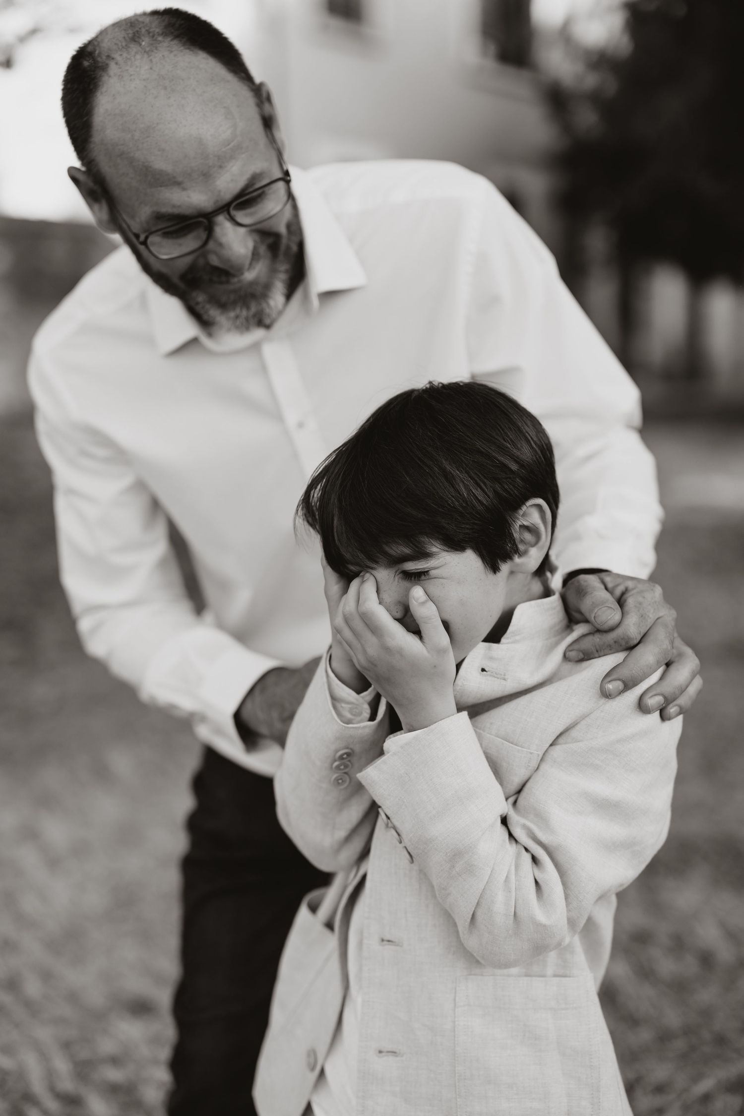 A candid black and white photo series showing a boy in a light colored suit covering his face in emotional moments.