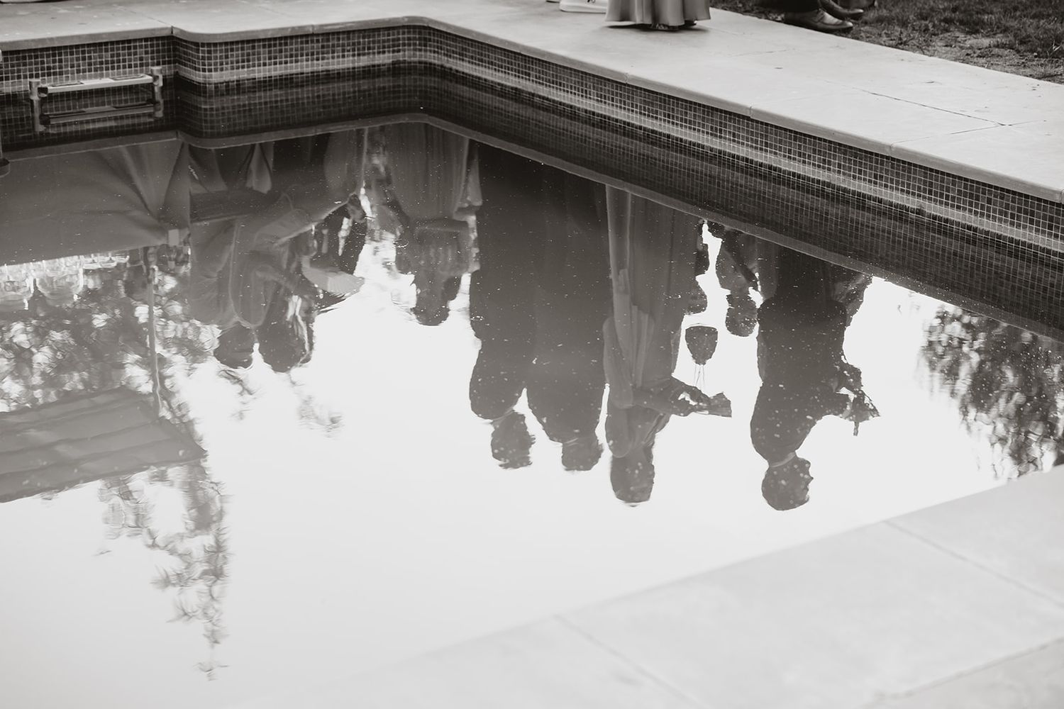 Reflection of wedding guests in a swimming pool creating a mirror image effect.