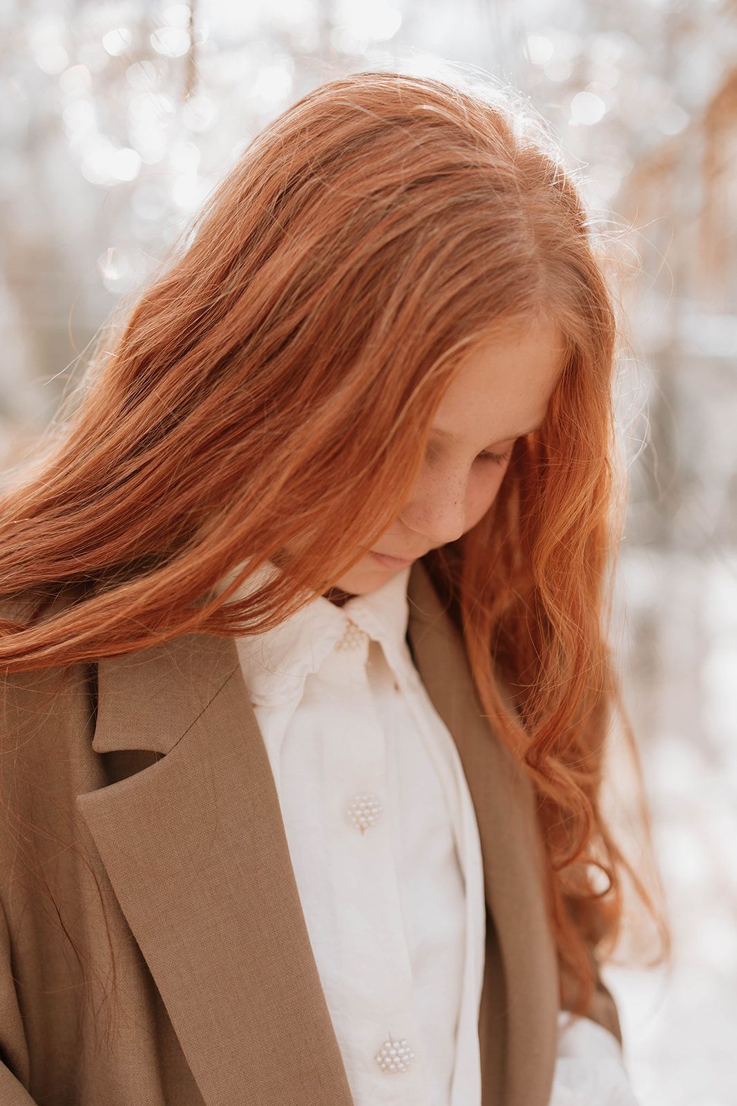 Delicate side profile portrait highlighting flowing copper hair and classic tailored style.
