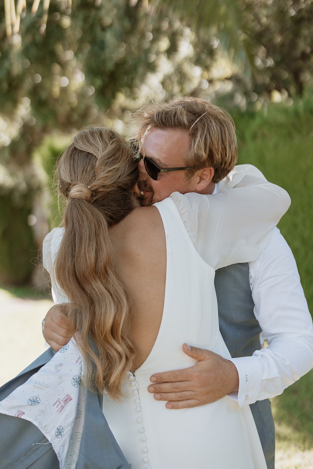 Two people share an emotional embrace during a wedding celebration outdoors.