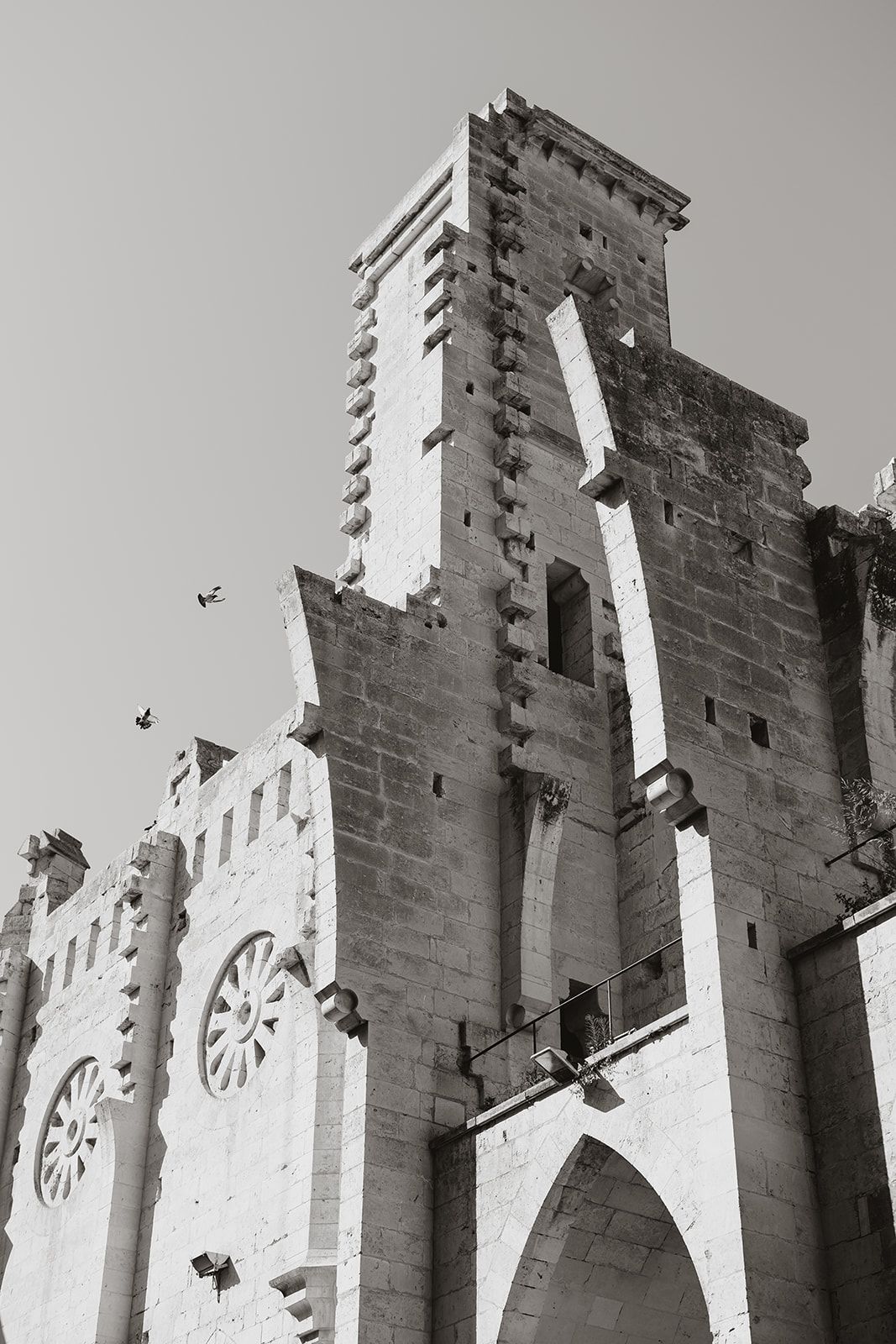 Black and white architectural photograph of a gothic church tower with dramatic stone details.