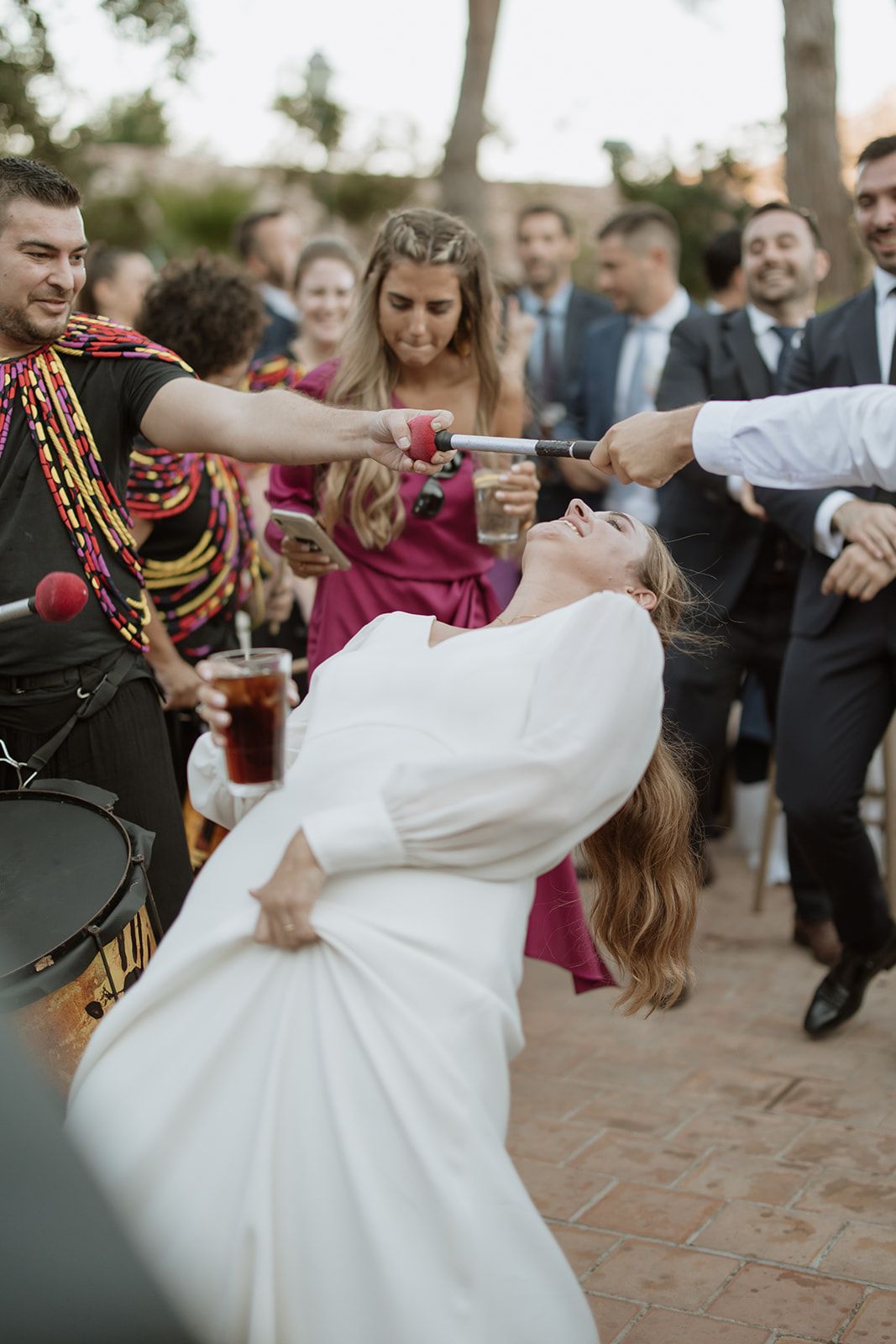 Energetic wedding guests dancing and celebrating on an outdoor patio.