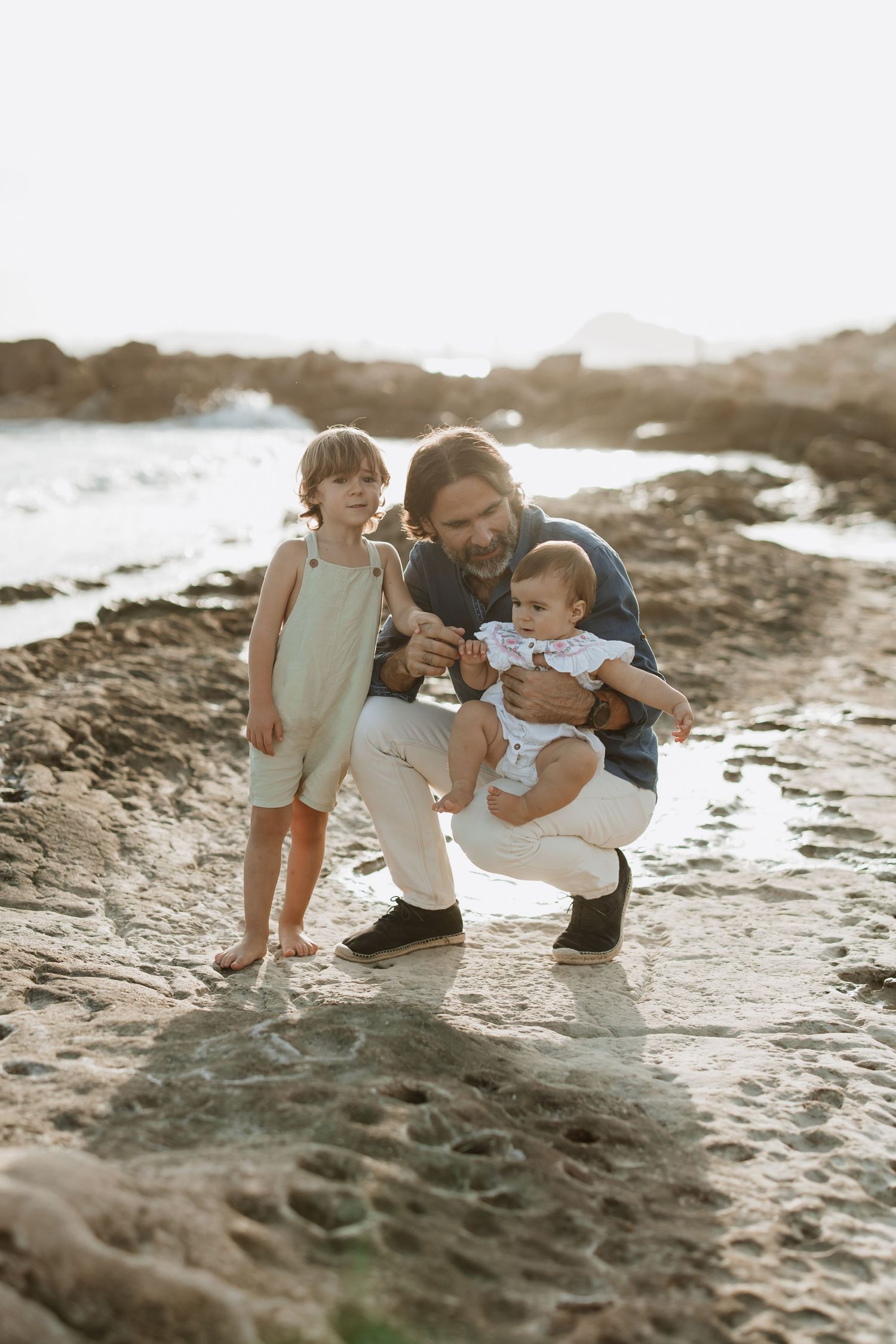 Family sharing laughs while exploring tide pools at sunset.