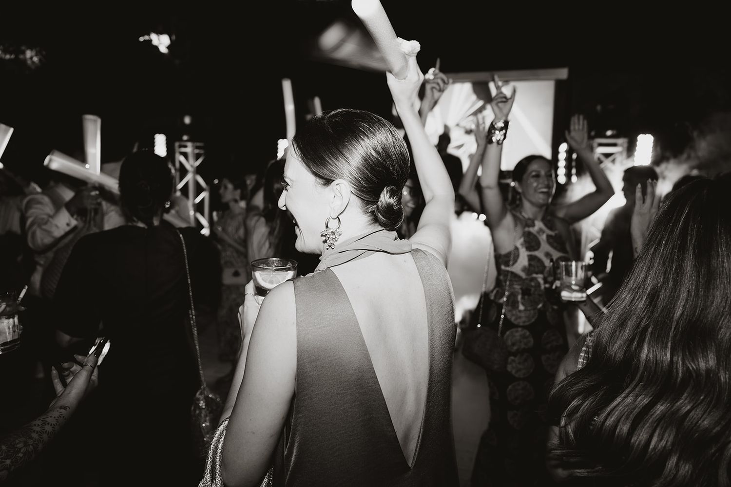 Silhouettes of people dancing and celebrating at a lively nighttime reception.