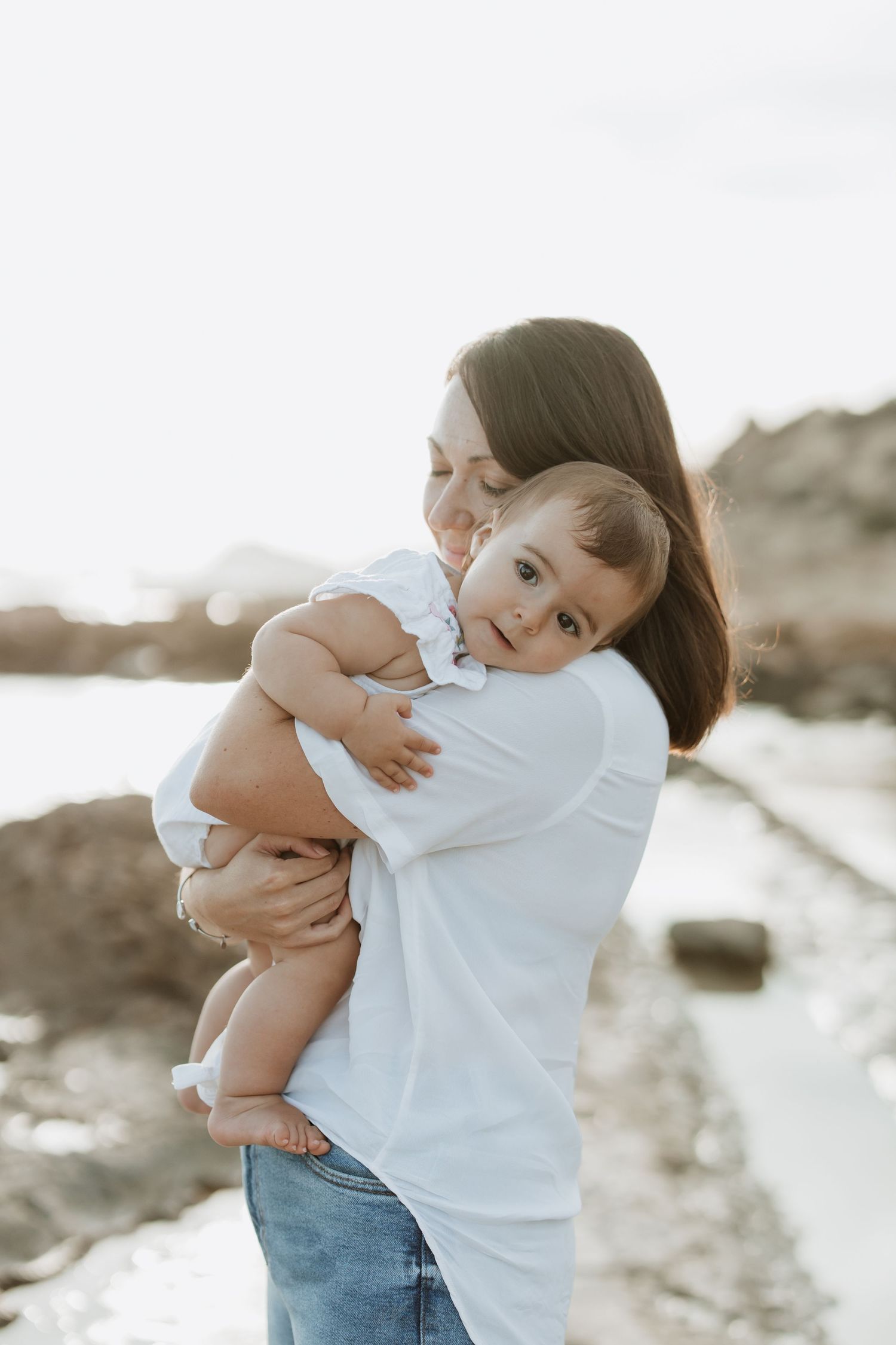 A loving embrace captured on a rocky beach during golden hour.