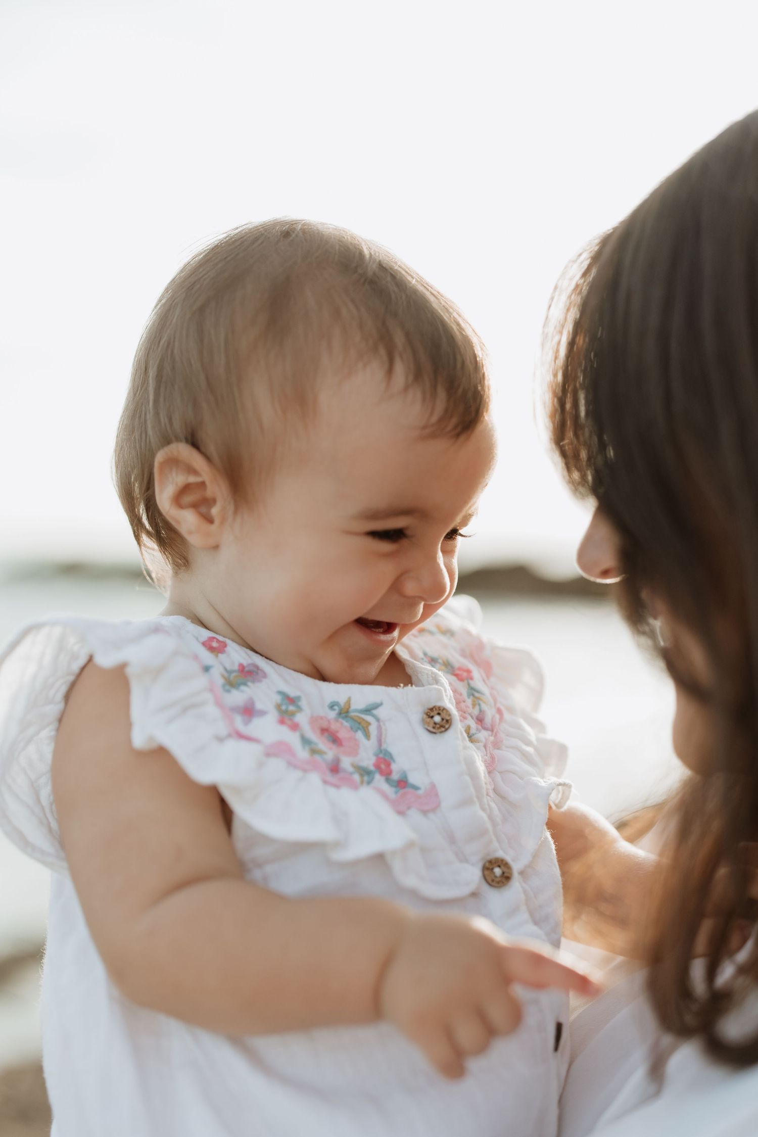 Candid moment of baby laughing while being held during sunset photoshoot.